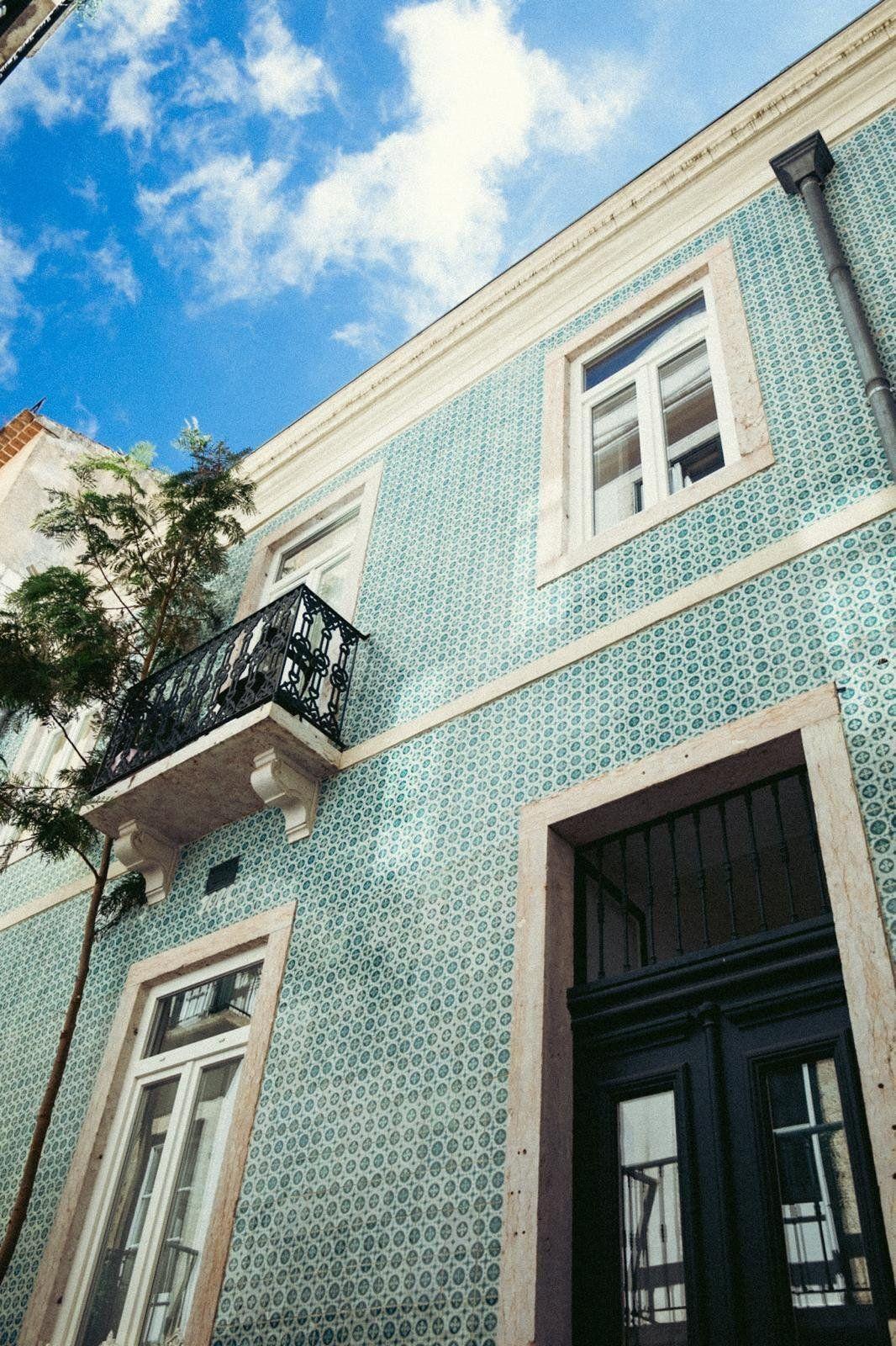 Exterior facade of the samesame building with traditional Portuguese blue azulejo tiles, balcony and dark wooden entrance door