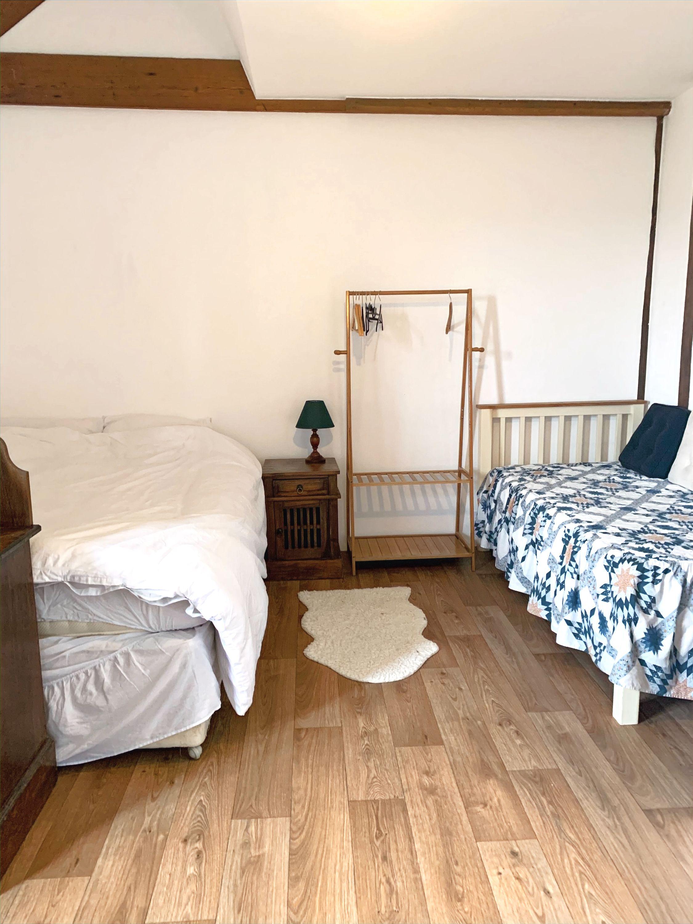 Private double room with two beds, wooden floor and clothes rack