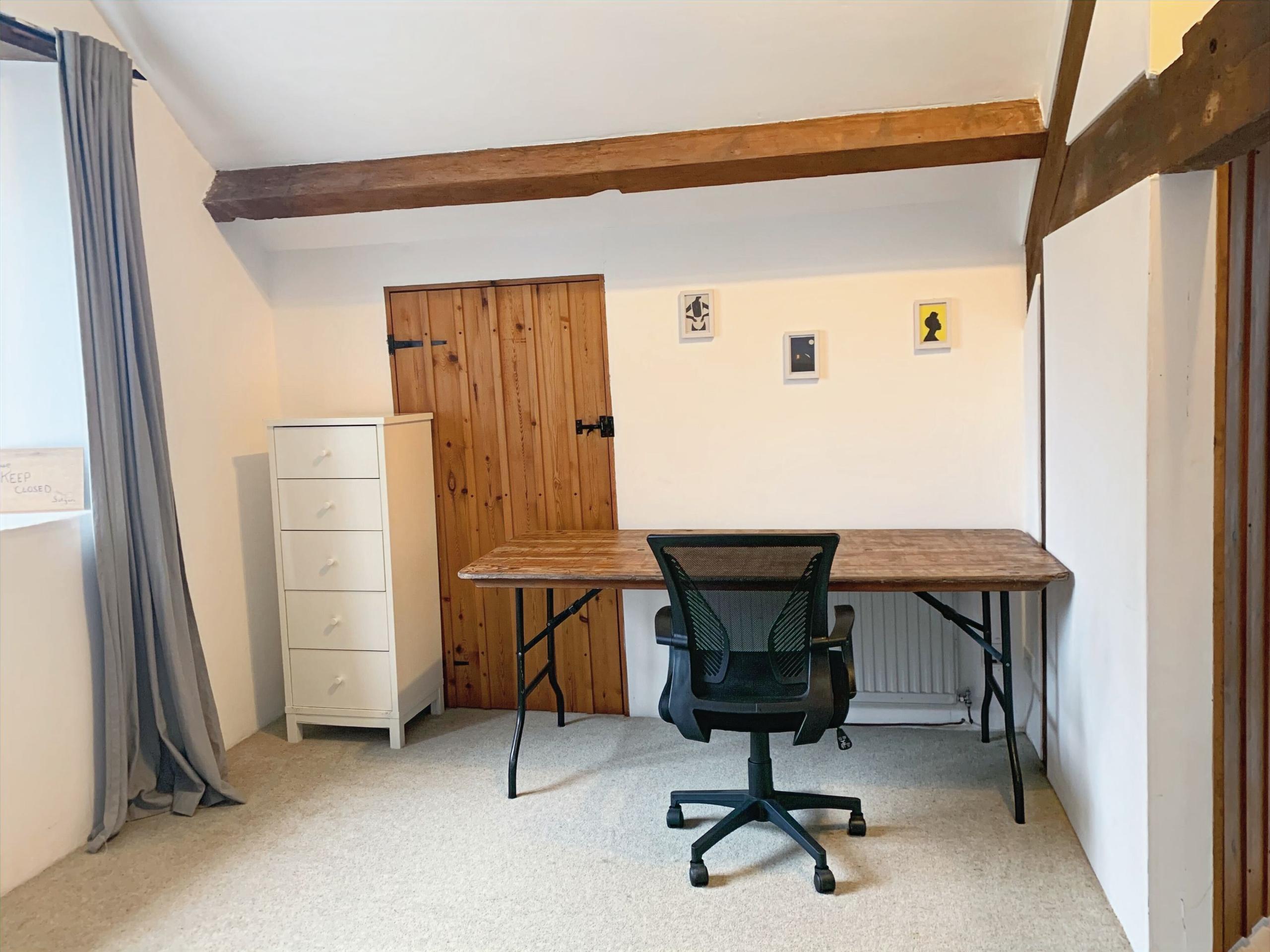 Large ensuite room with desk, office chair and exposed wooden beams