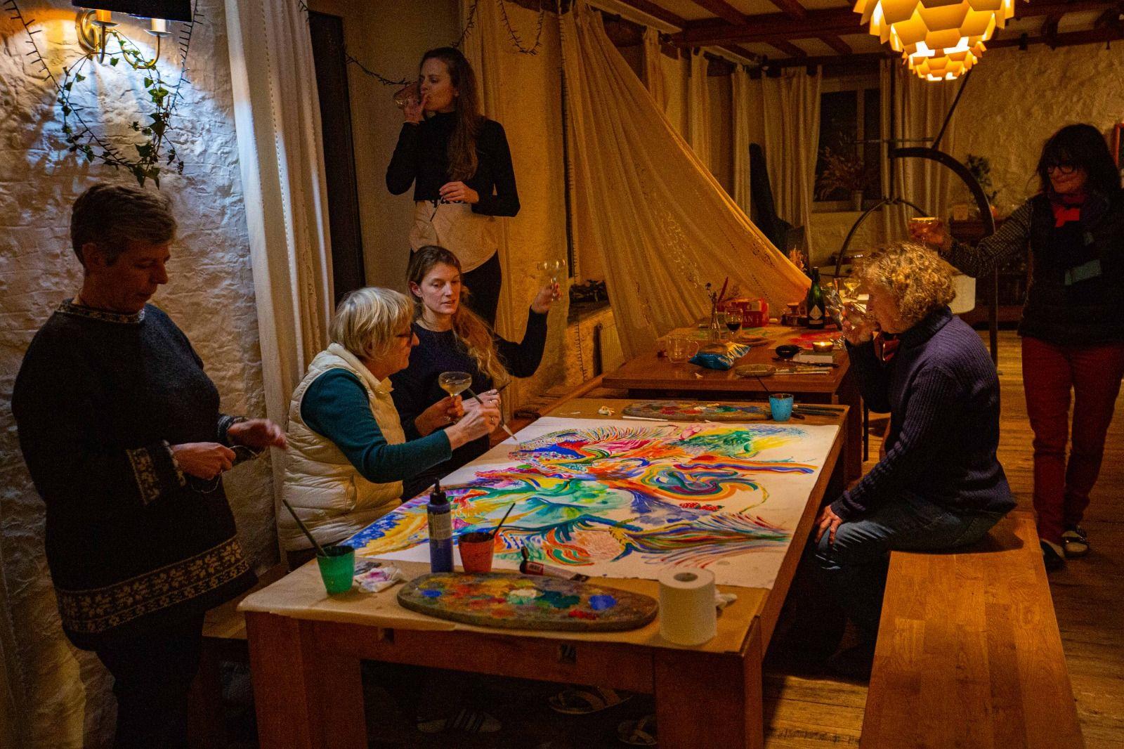 Colivers gathered around a large painting on the dining table during an art session