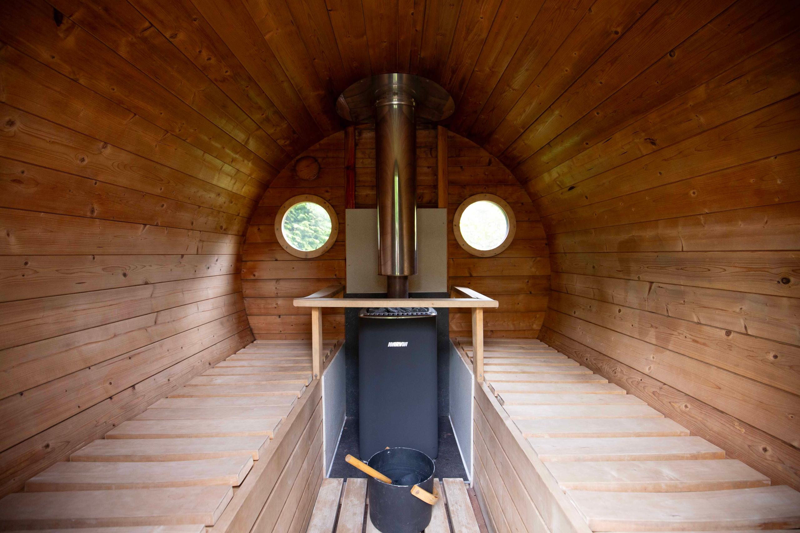 Interior of the barrel sauna with wooden benches and stove