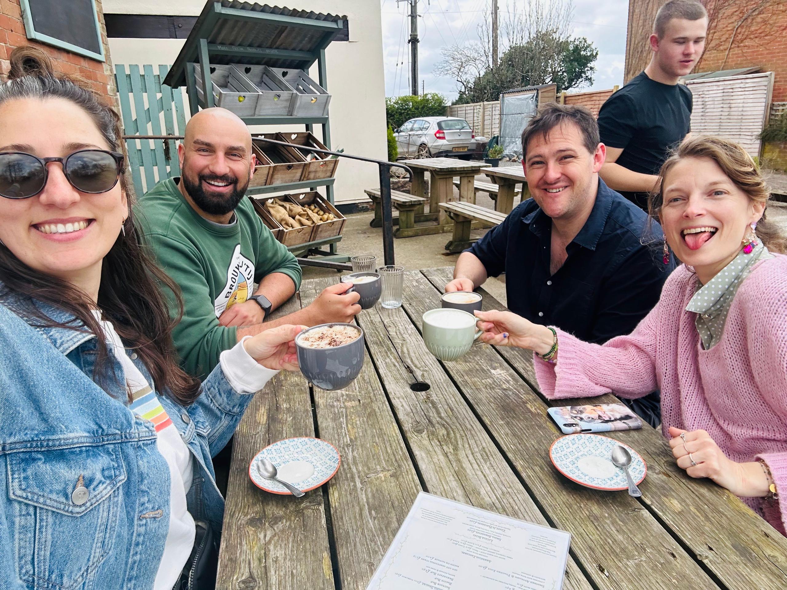 Group of four colivers enjoying drinks together at an outdoor café table