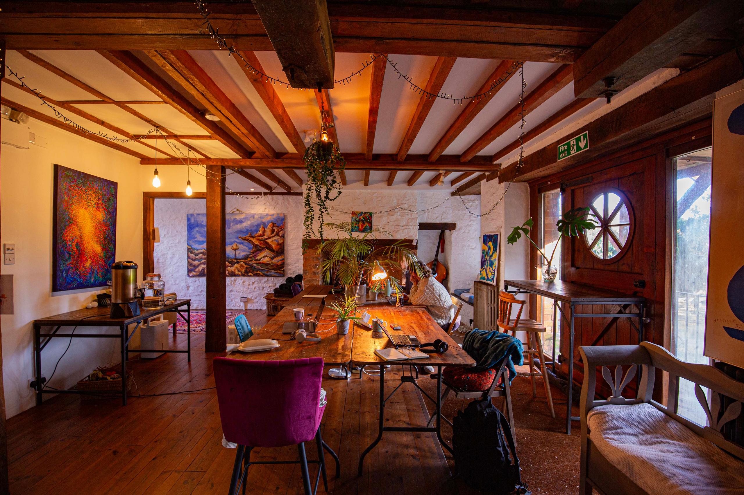 The first floor dining room with long wooden table, colourful artwork and fairy lights