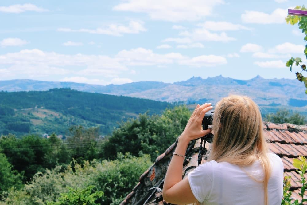 A girl looking over the mountains with binoculars. Elie is looking over Portuguese border from the garden. This is the view that you will see from coworking spaces.