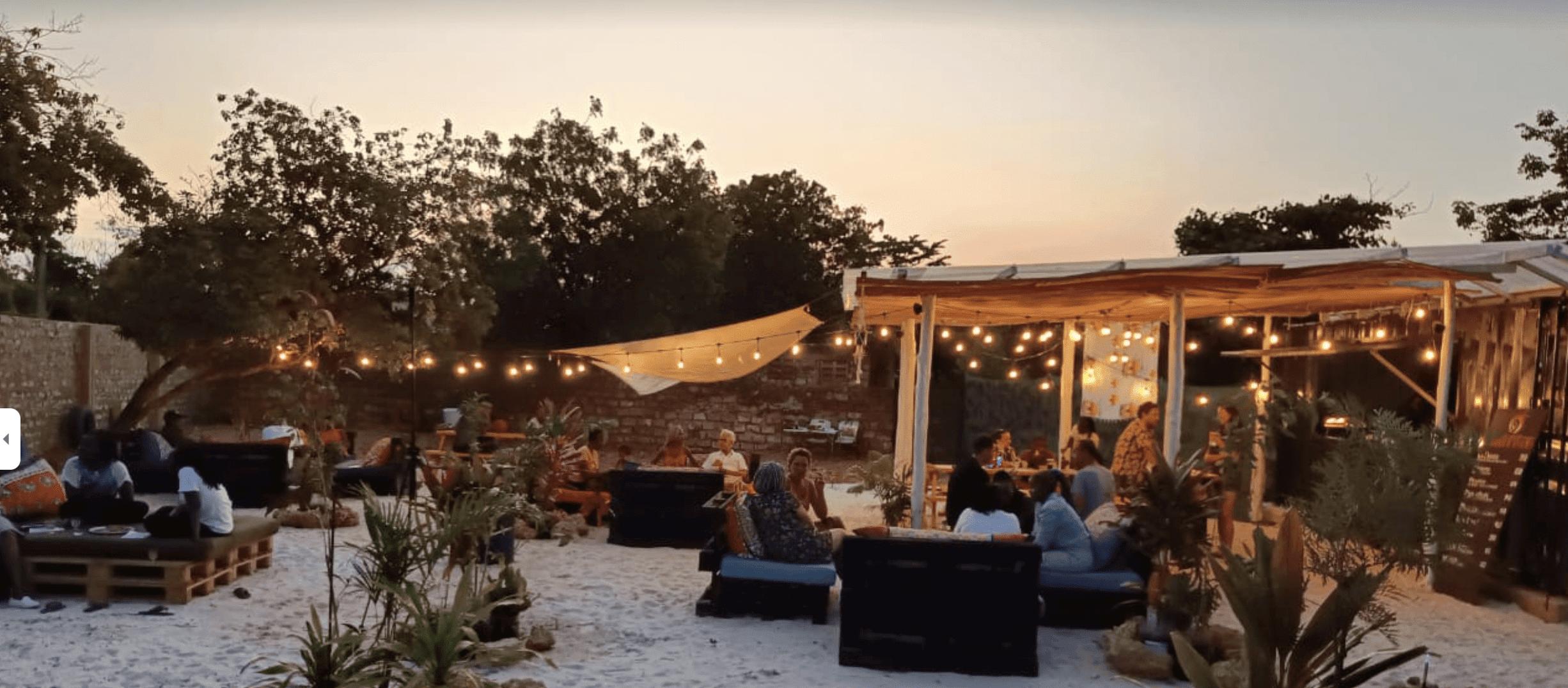 Guests relaxing at the outdoor lounge area at sunset with string lights