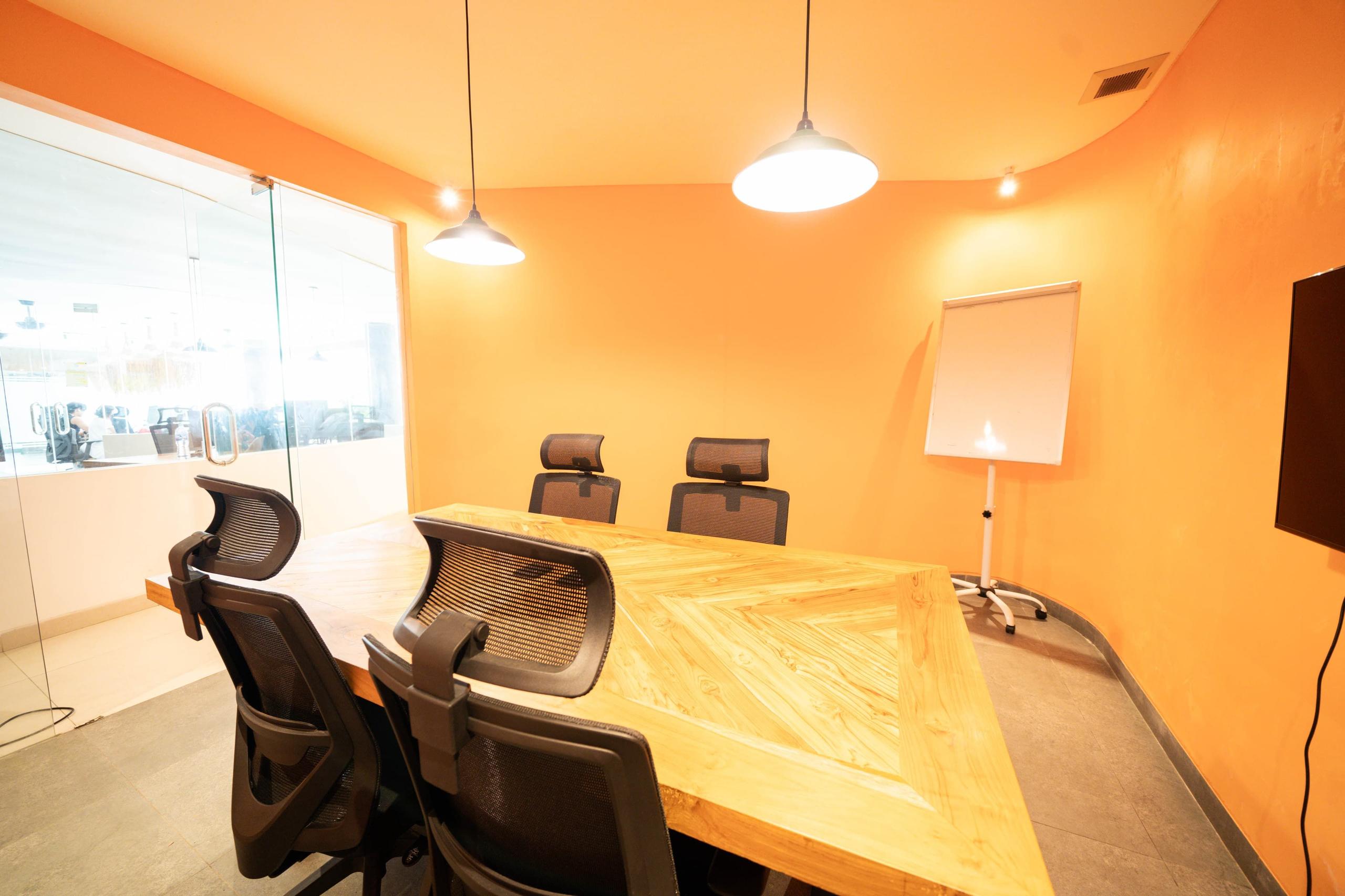 Spacious conference room with large screen and whiteboard, accommodating 6–10 people