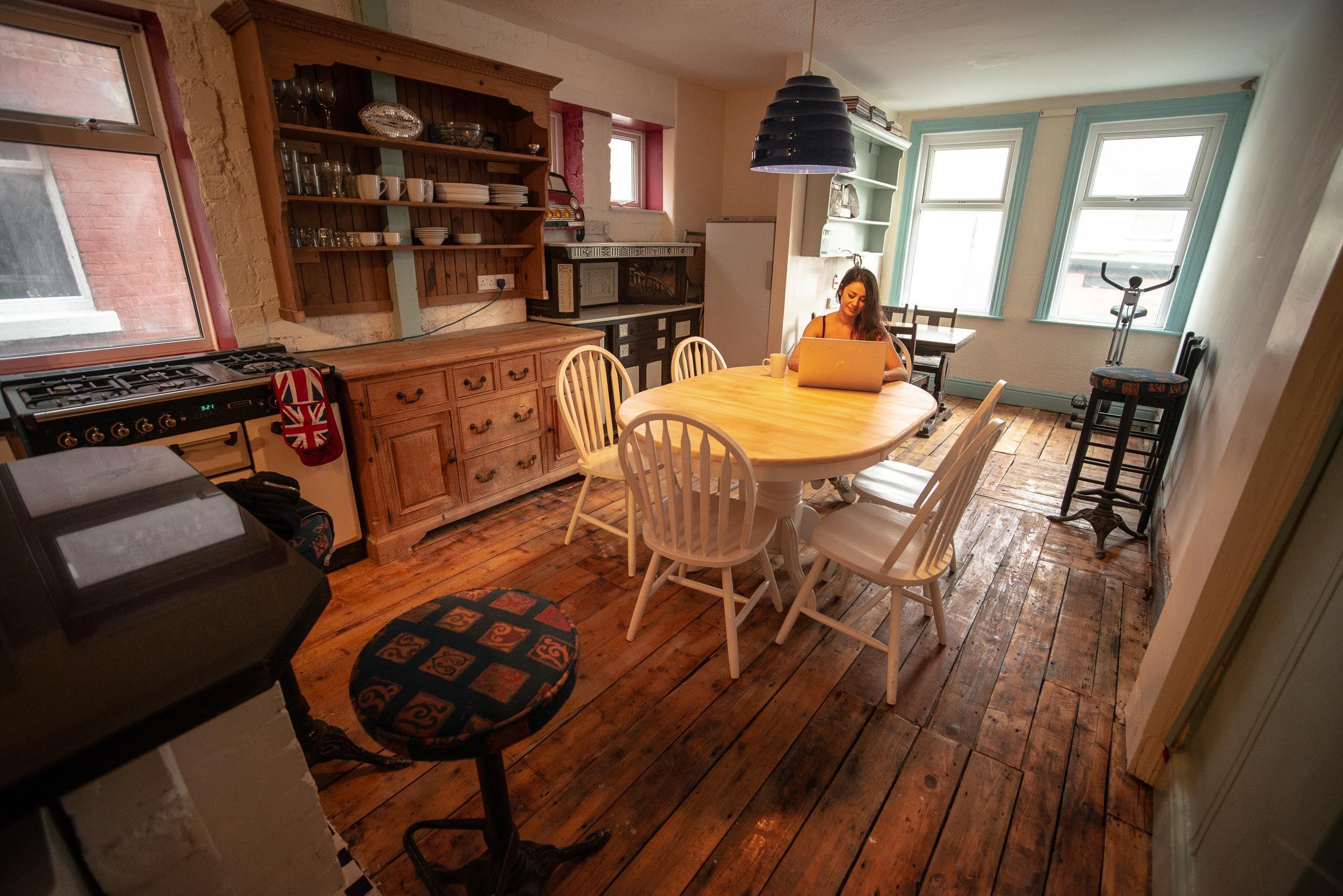 Person working on a laptop at the dining table in the kitchen coliving room