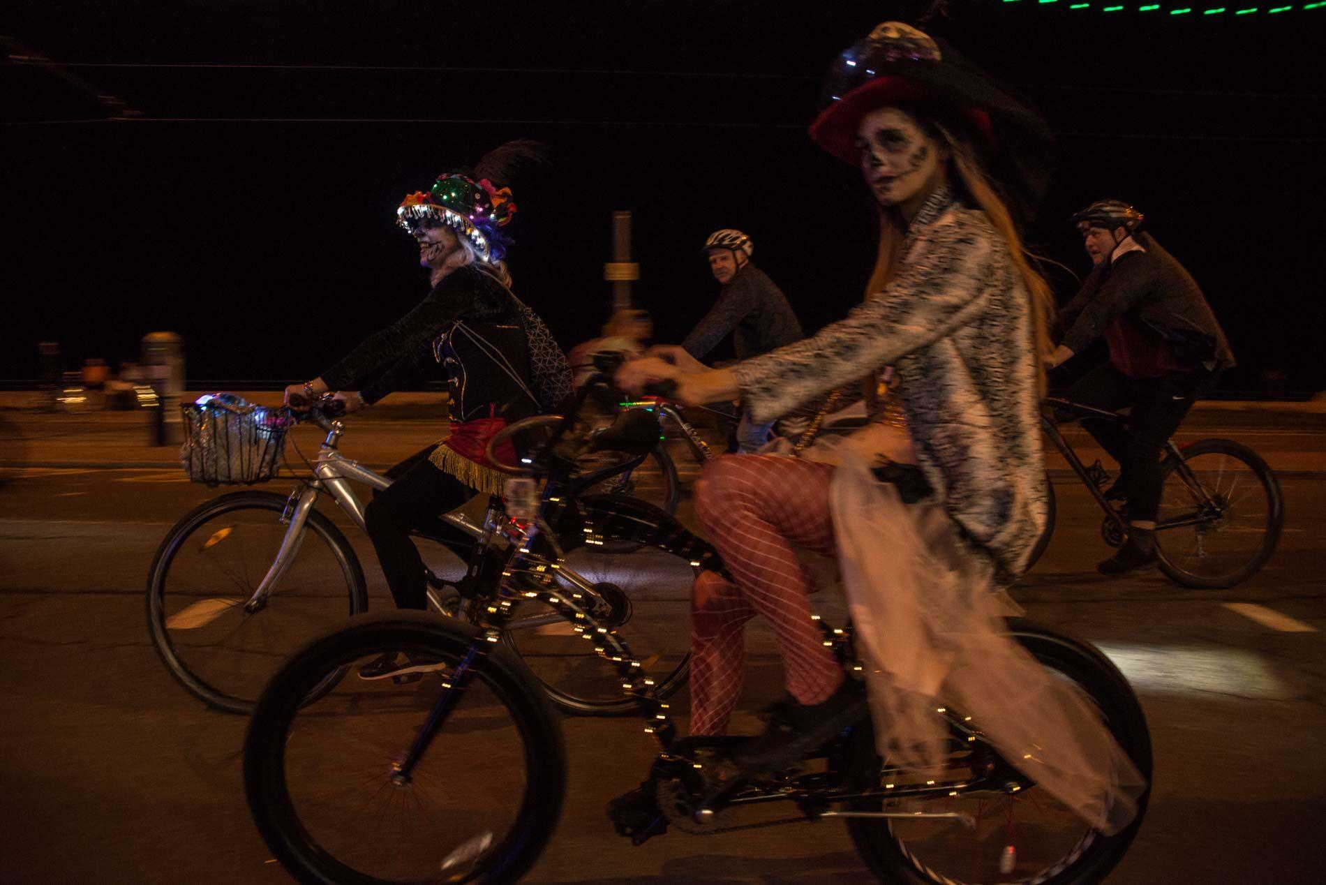 People cycling in Halloween costumes along Blackpool promenade at night