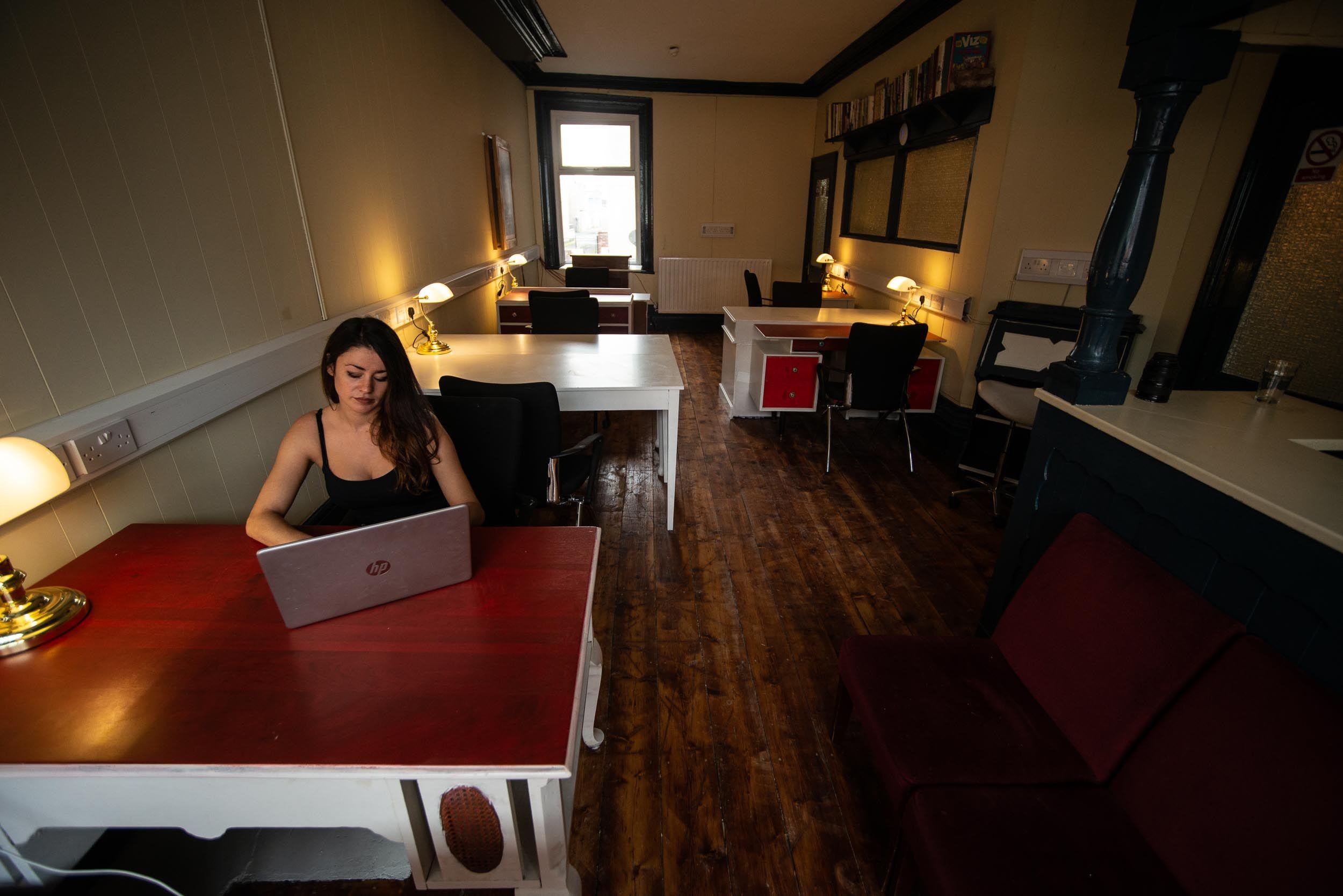 The main coworking room showing the bar area with red sofas and large bay window