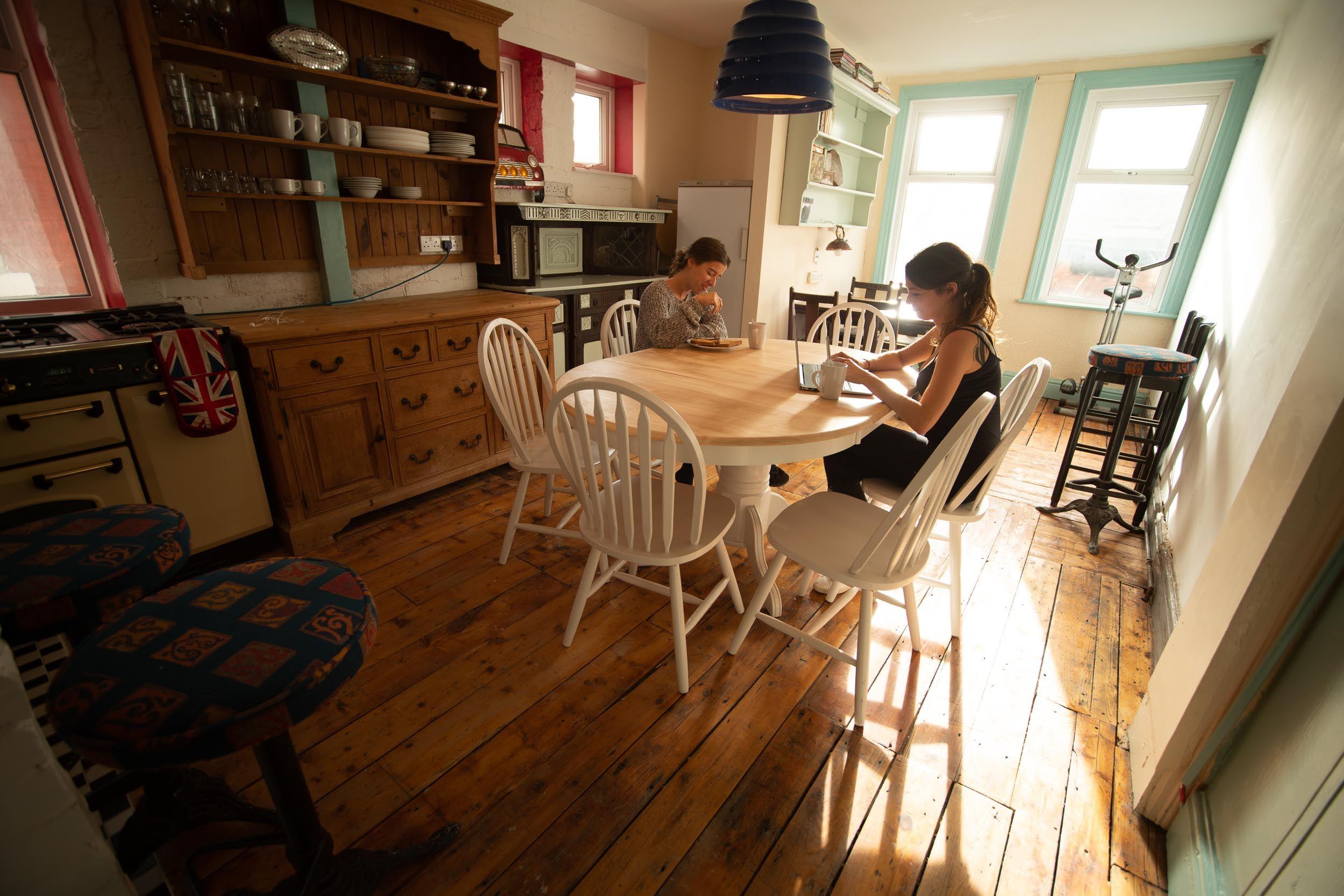 Two people sitting at the dining table in the bright kitchen and coliving area
