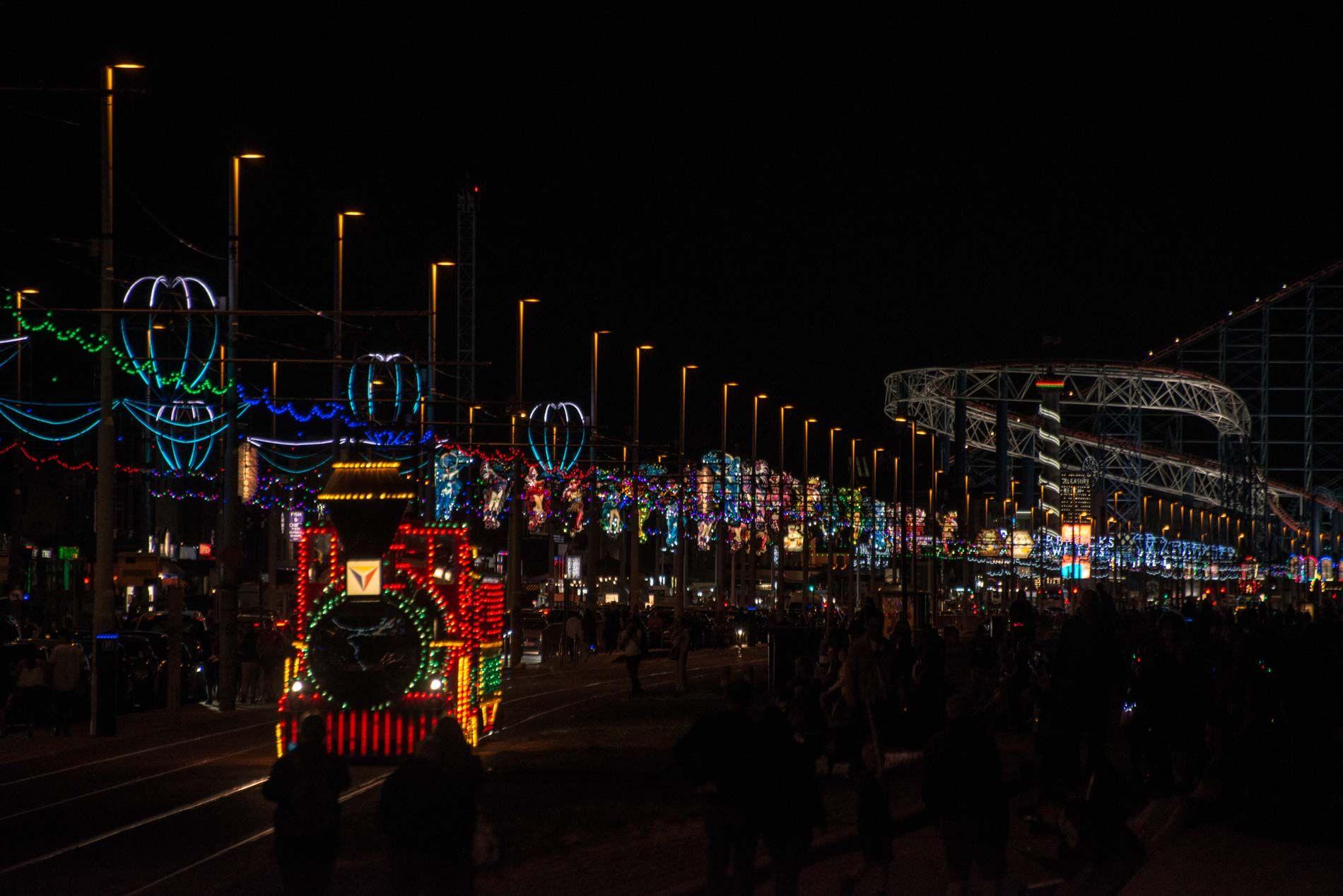 Blackpool Illuminations at night with tram and fairground rides lit up