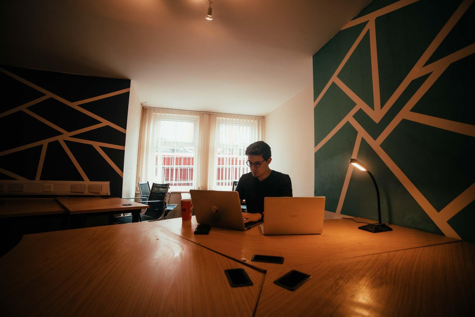 Person working on a laptop in the quiet coworking basement room with geometric wall art