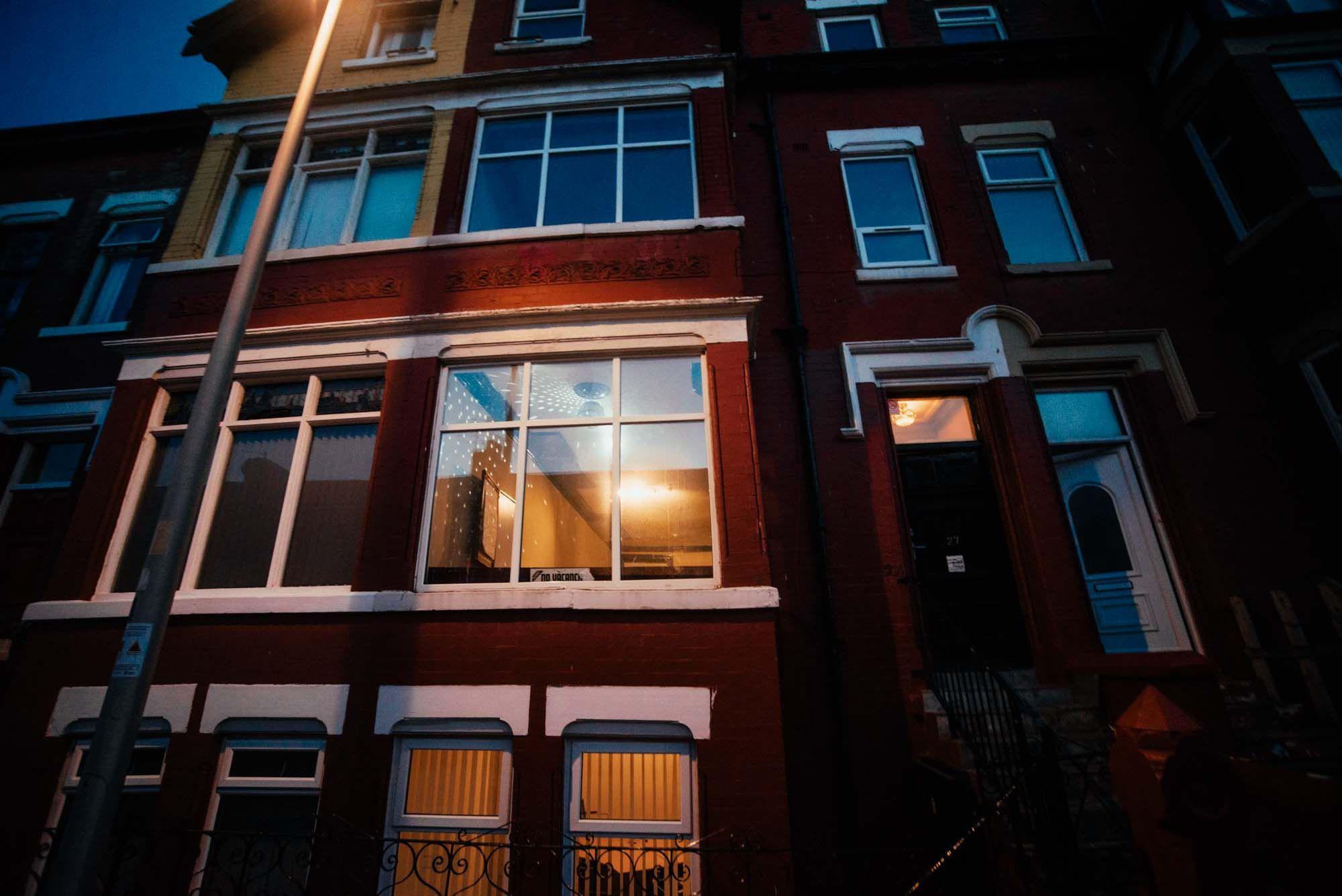 The Victorian coliving house exterior at night, showing the red brick facade and lit windows