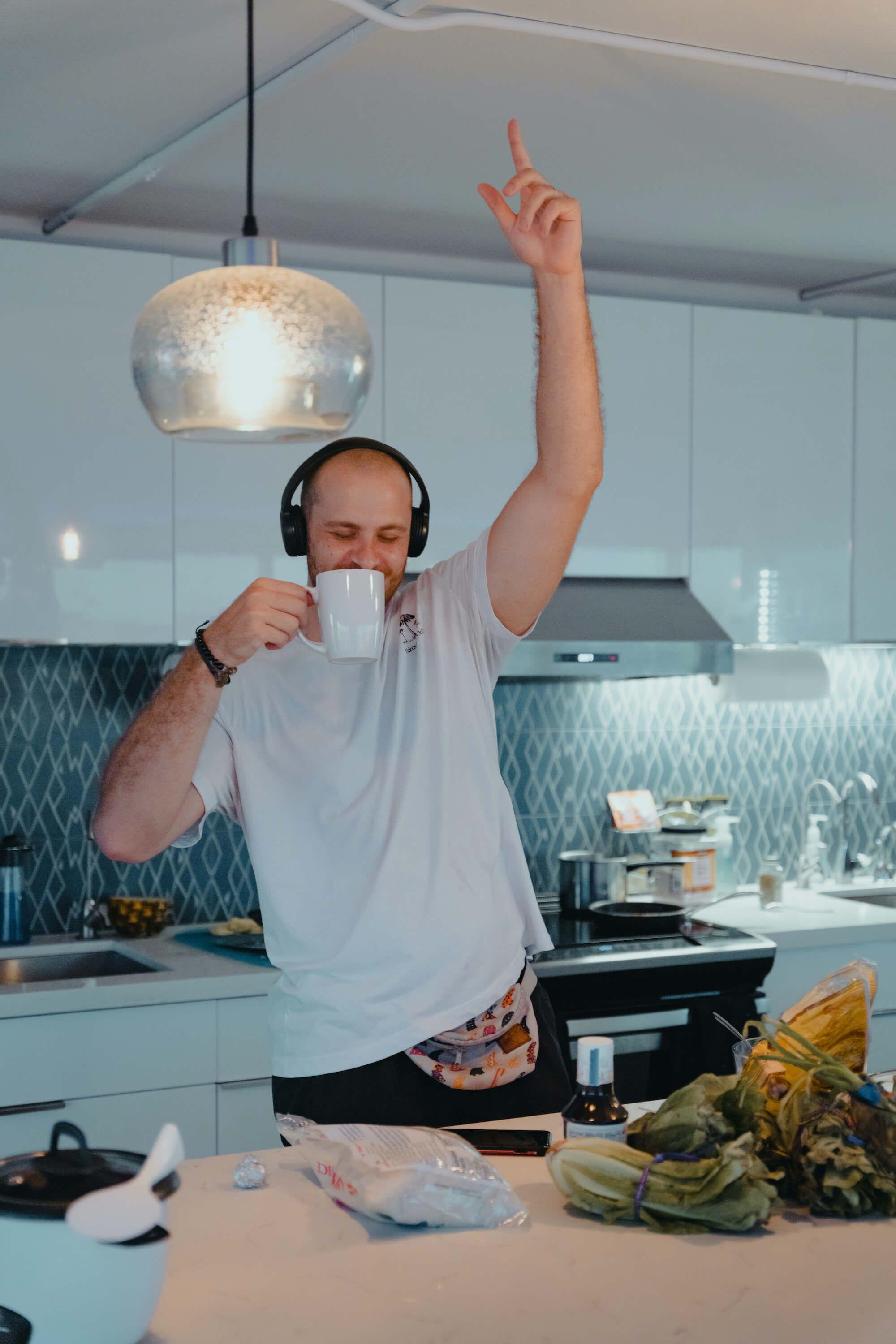Member with headphones dancing and drinking coffee in the shared kitchen