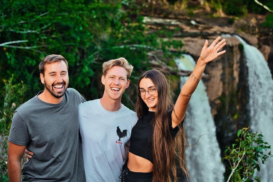Three Surfbreak members smiling and posing in front of a waterfall during a group outing
