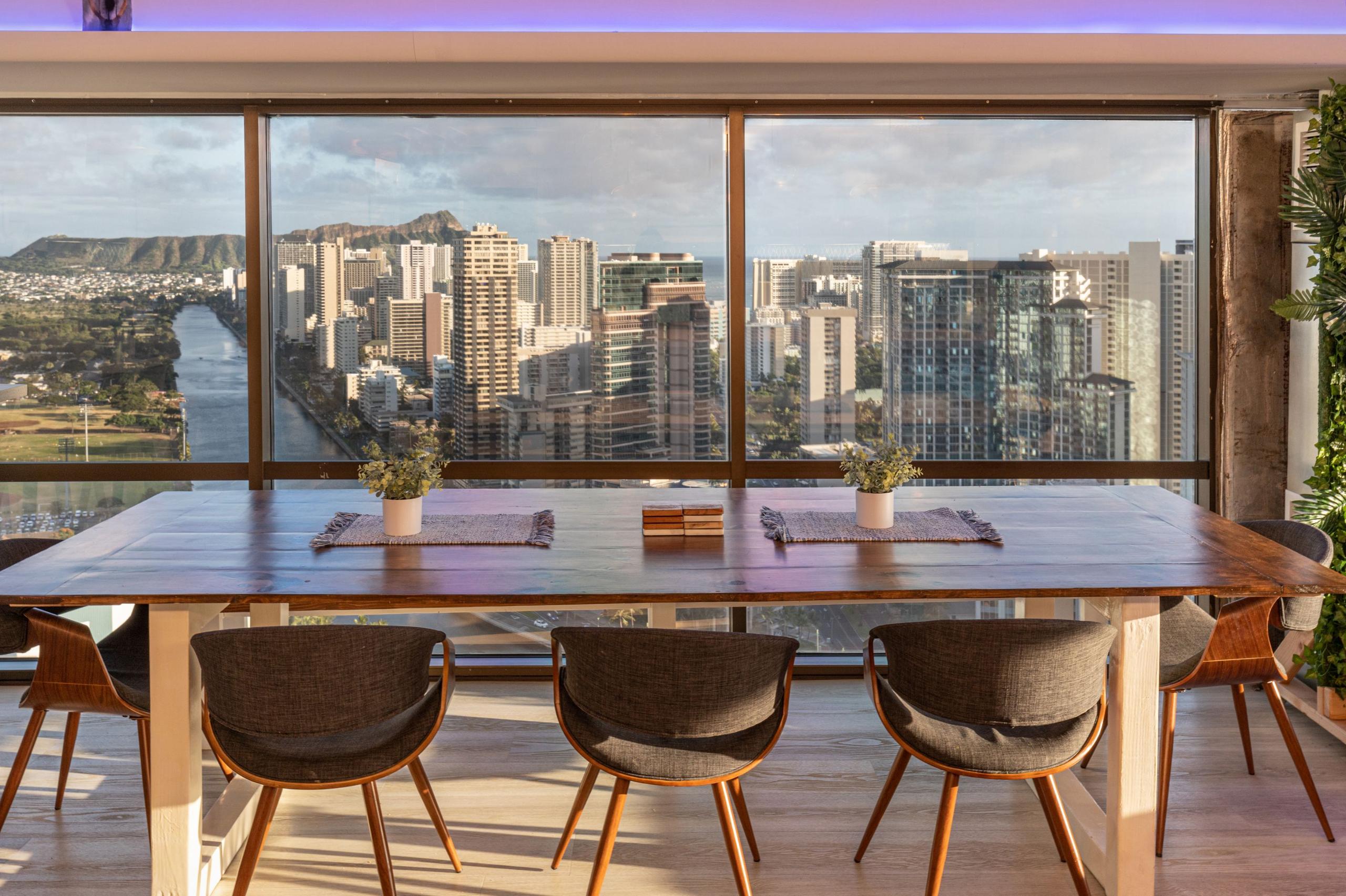 Dining table with chairs and panoramic views of Honolulu, Ala Wai Canal, and Diamond Head through floor-to-ceiling windows