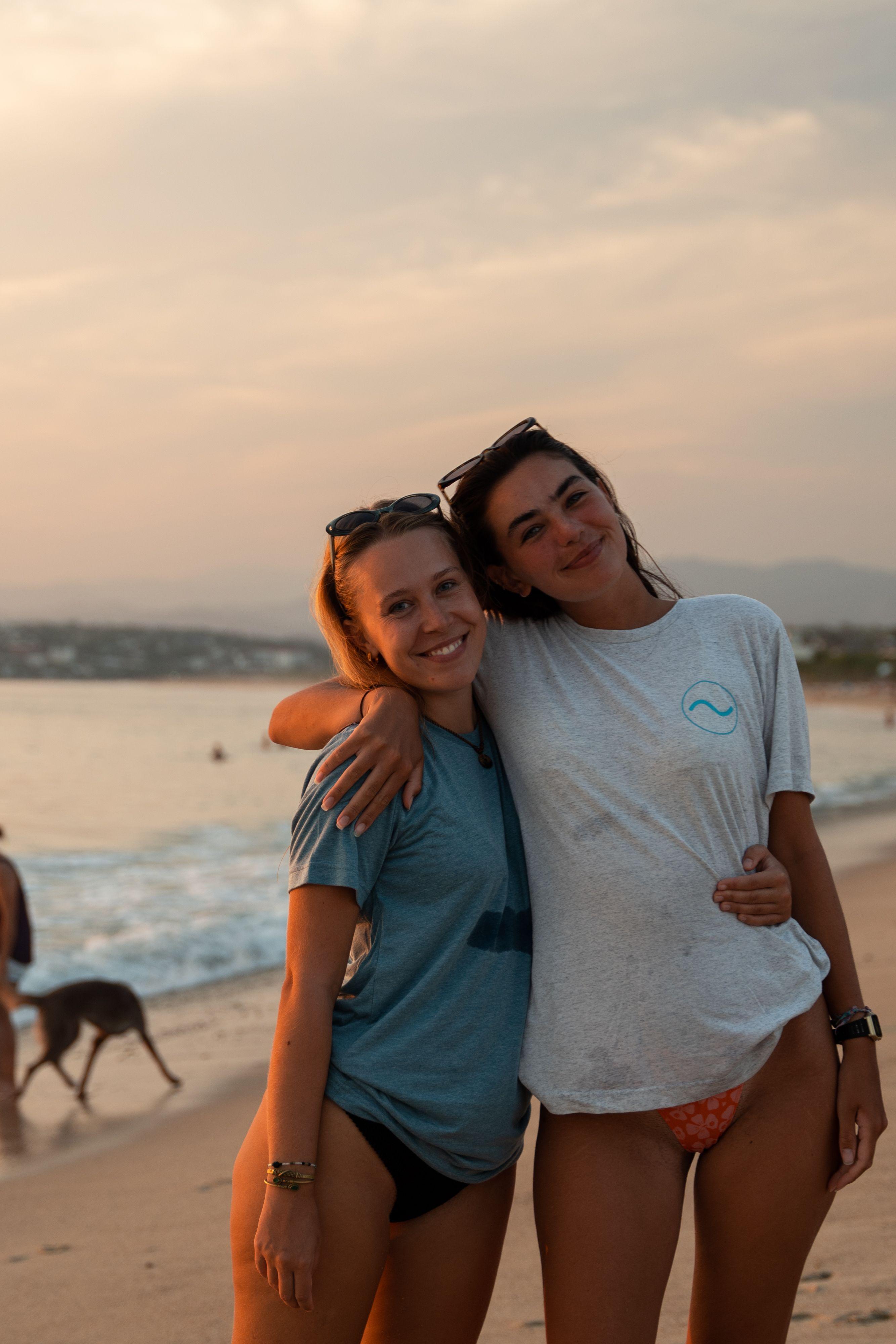 Two female members posing together on the beach at sunset in Puerto Escondido