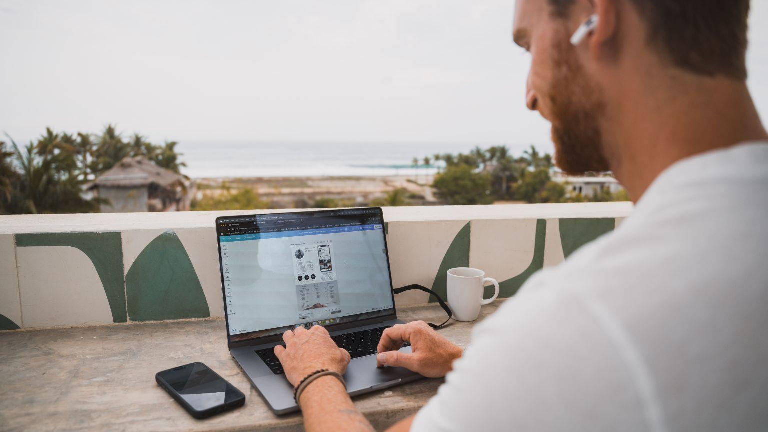 A member working on a laptop on the rooftop terrace with ocean view in the background