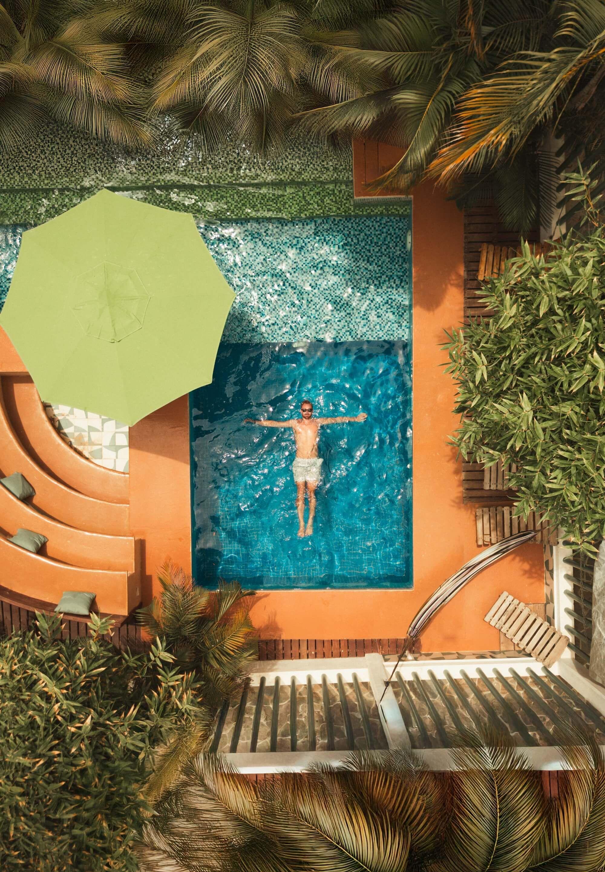 Aerial view of the private in-ground pool with sunbathing area, umbrella, and tropical garden at Surfbreak PXM