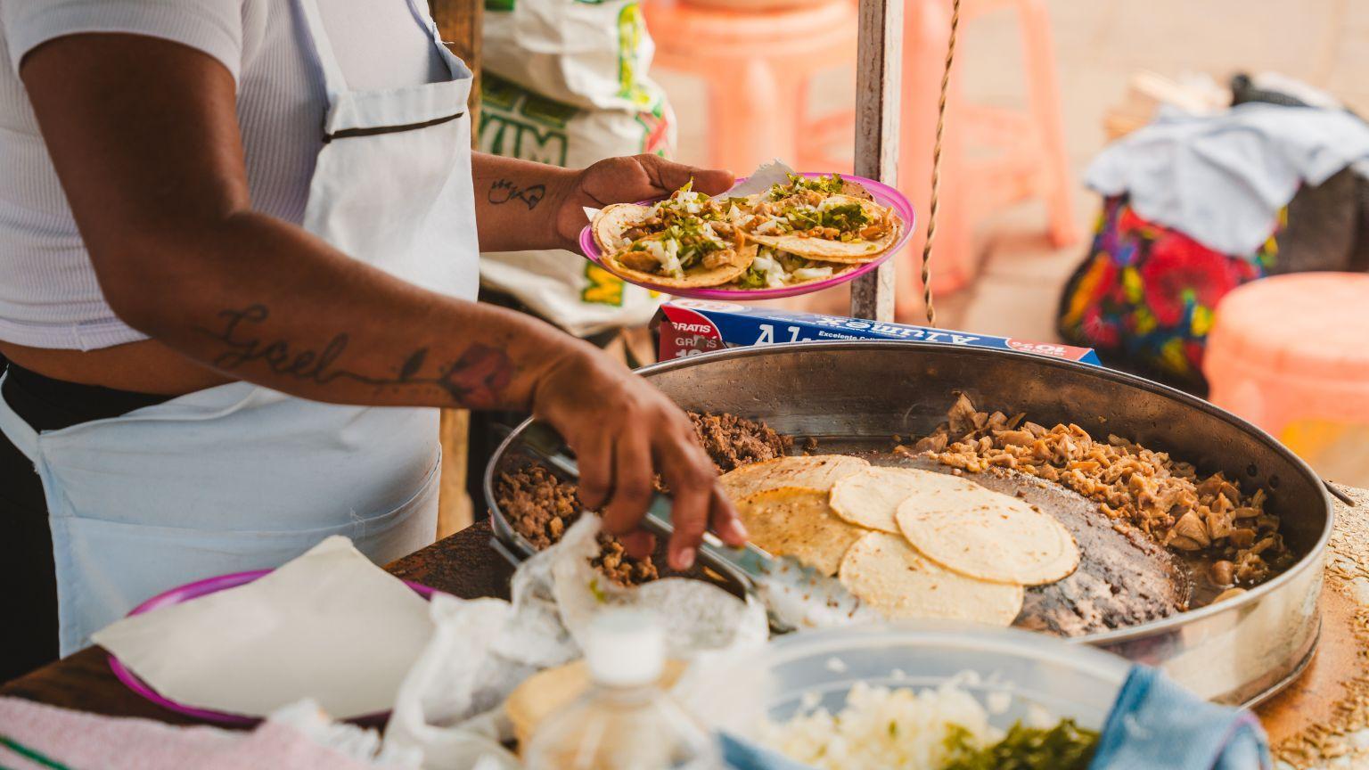 A local street food vendor preparing tacos at a market stall in Puerto Escondido