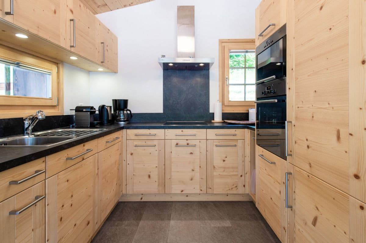 Fully equipped self-catering kitchen in the Swiss Escape chalet with wooden cabinets, Nespresso machine, oven, and modern appliances