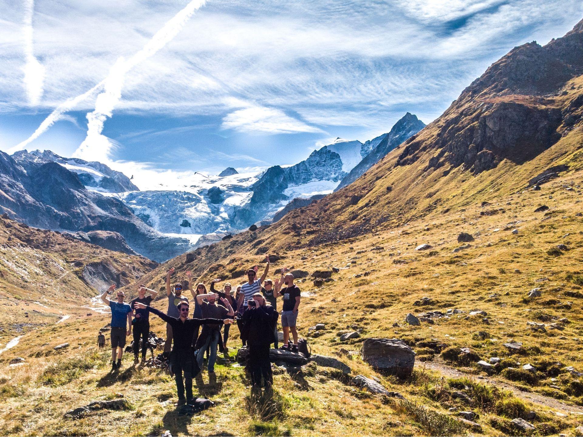 Group of Swiss Escape guests celebrating on a mountain hike with glacier views in the Swiss Alps