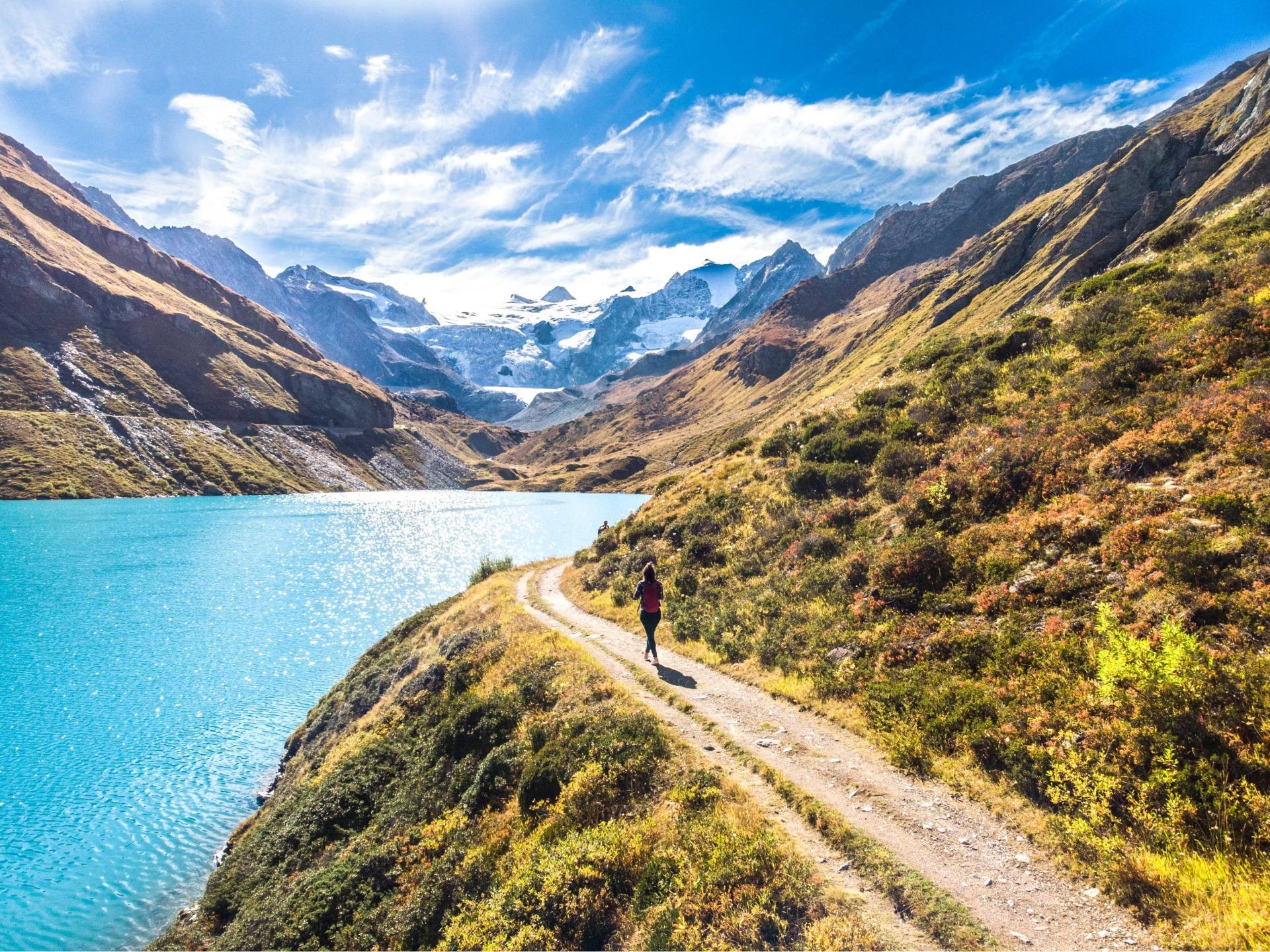 Person hiking around Moiry dam in autumn