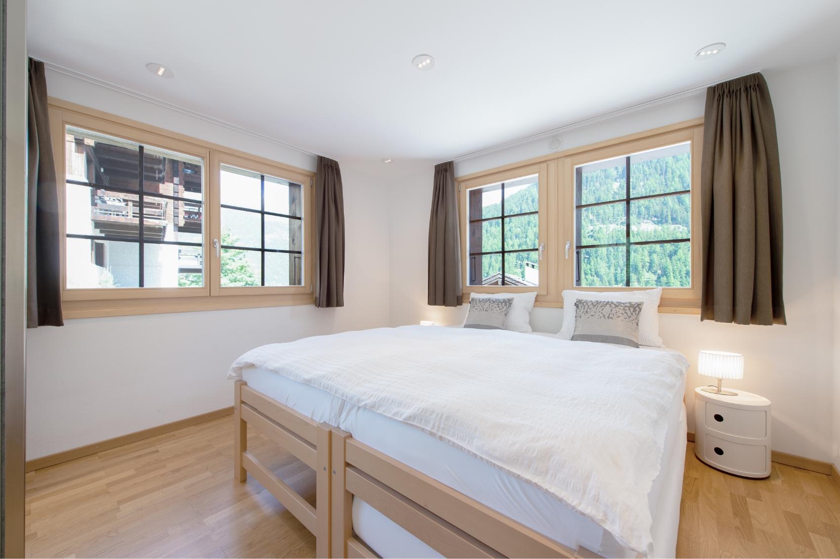 Private double room with a queen/king bed, wooden frame, and windows overlooking the mountains