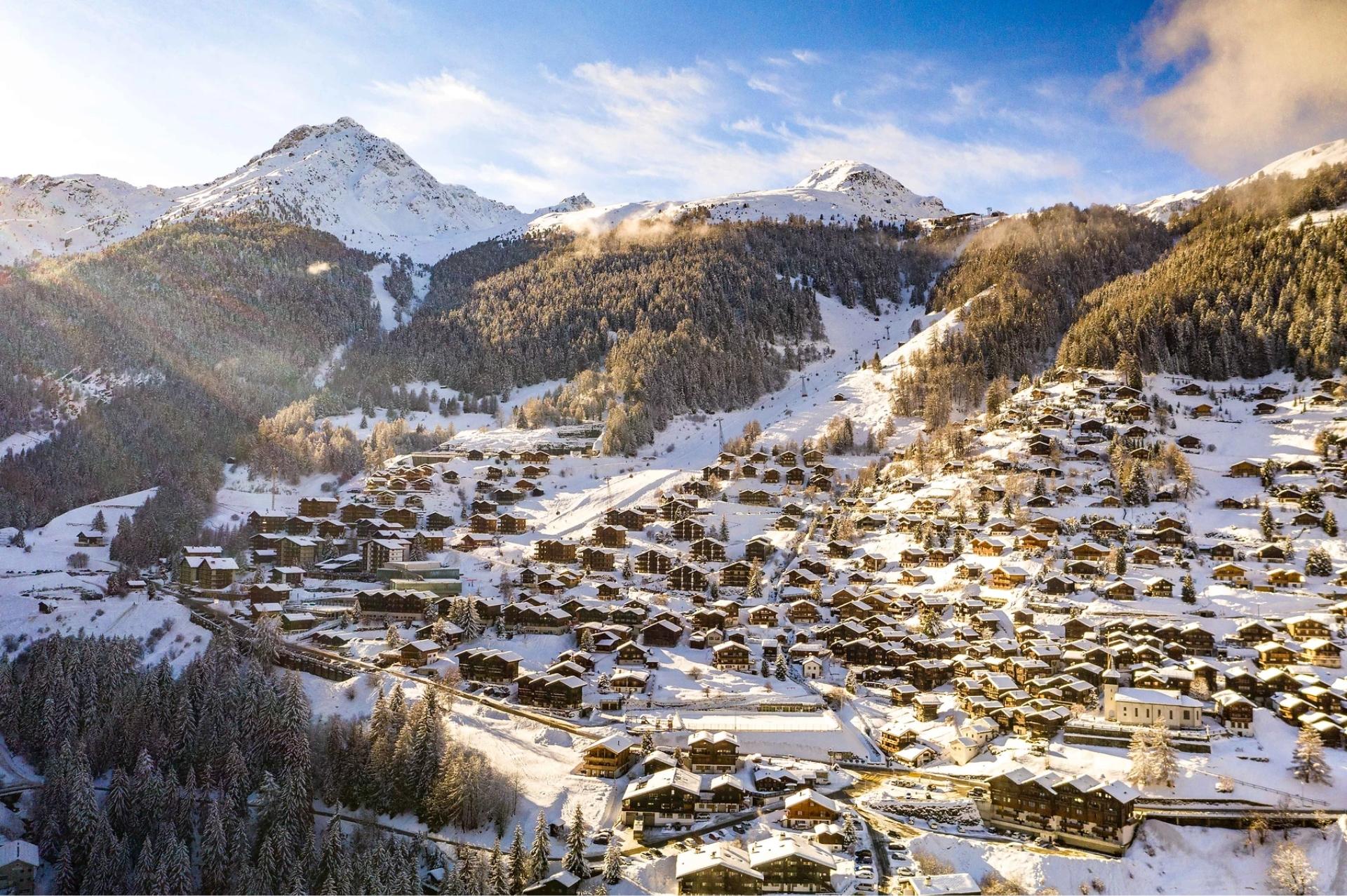 Aerial view of the snowy mountain village of Grimentz in winter, surrounded by the Swiss Alps