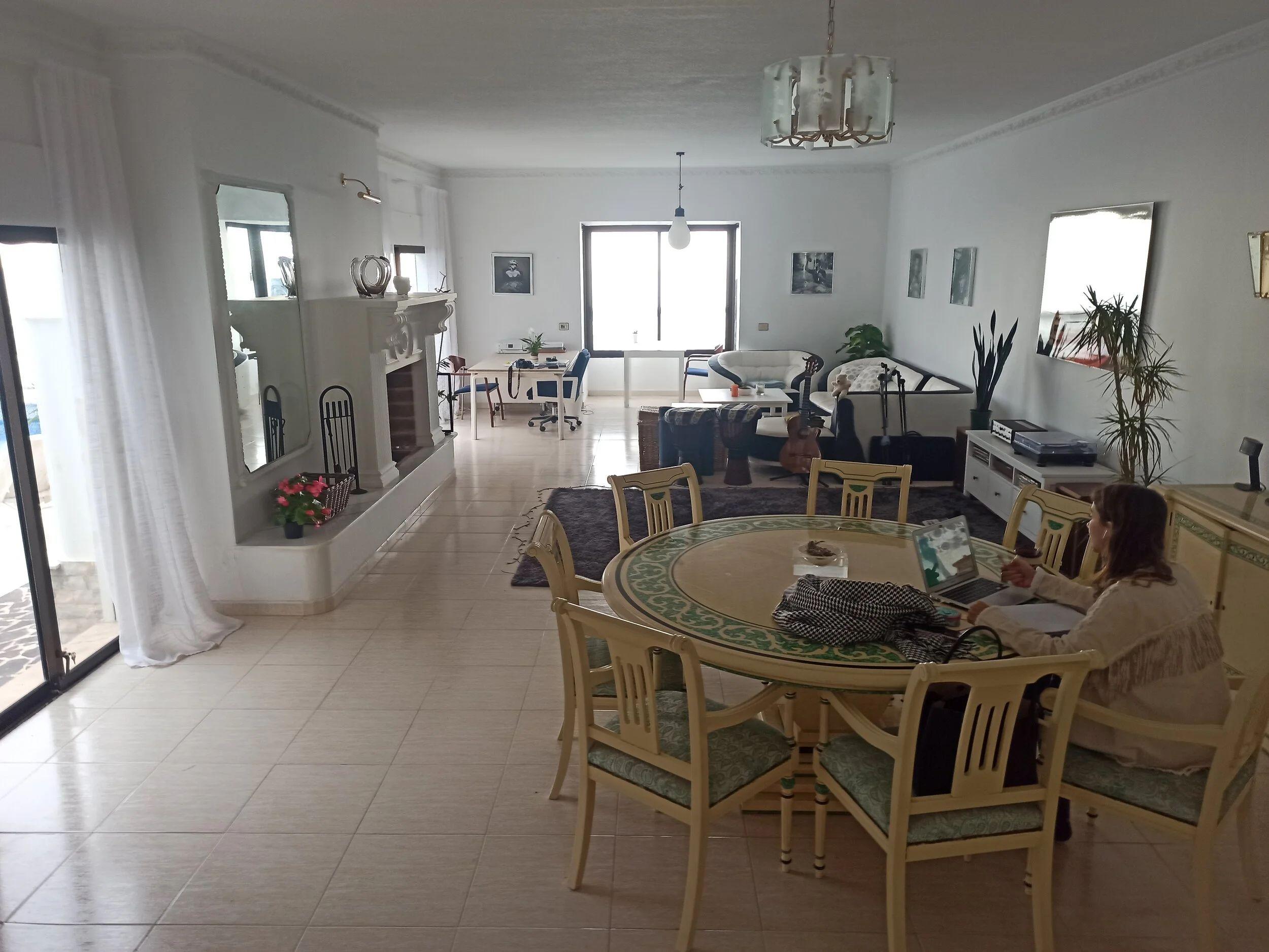 Spacious main hall living area with dining table, fireplace and workstations