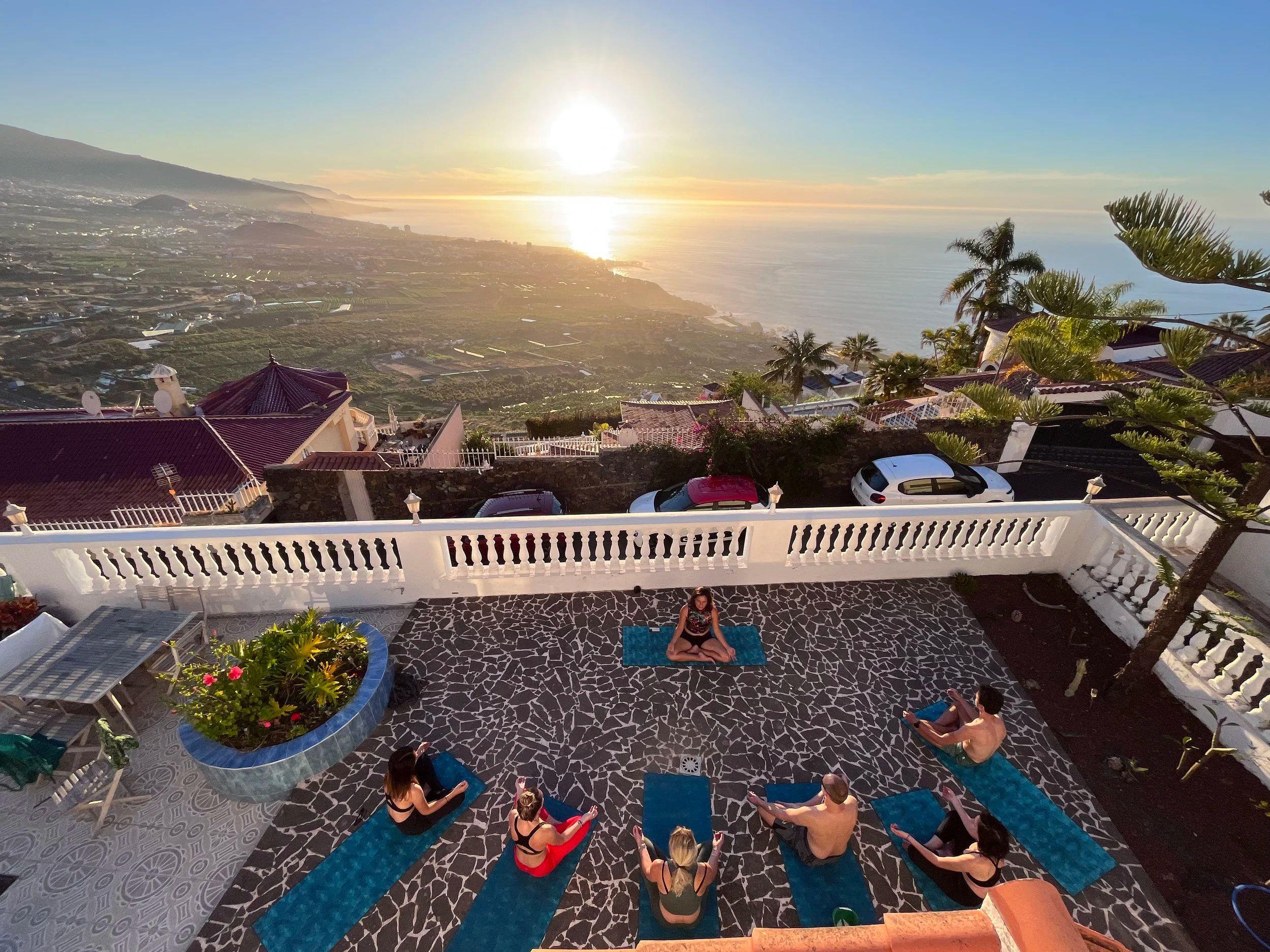 Group yoga session on the upper deck terrace at sunset with panoramic valley and sea views