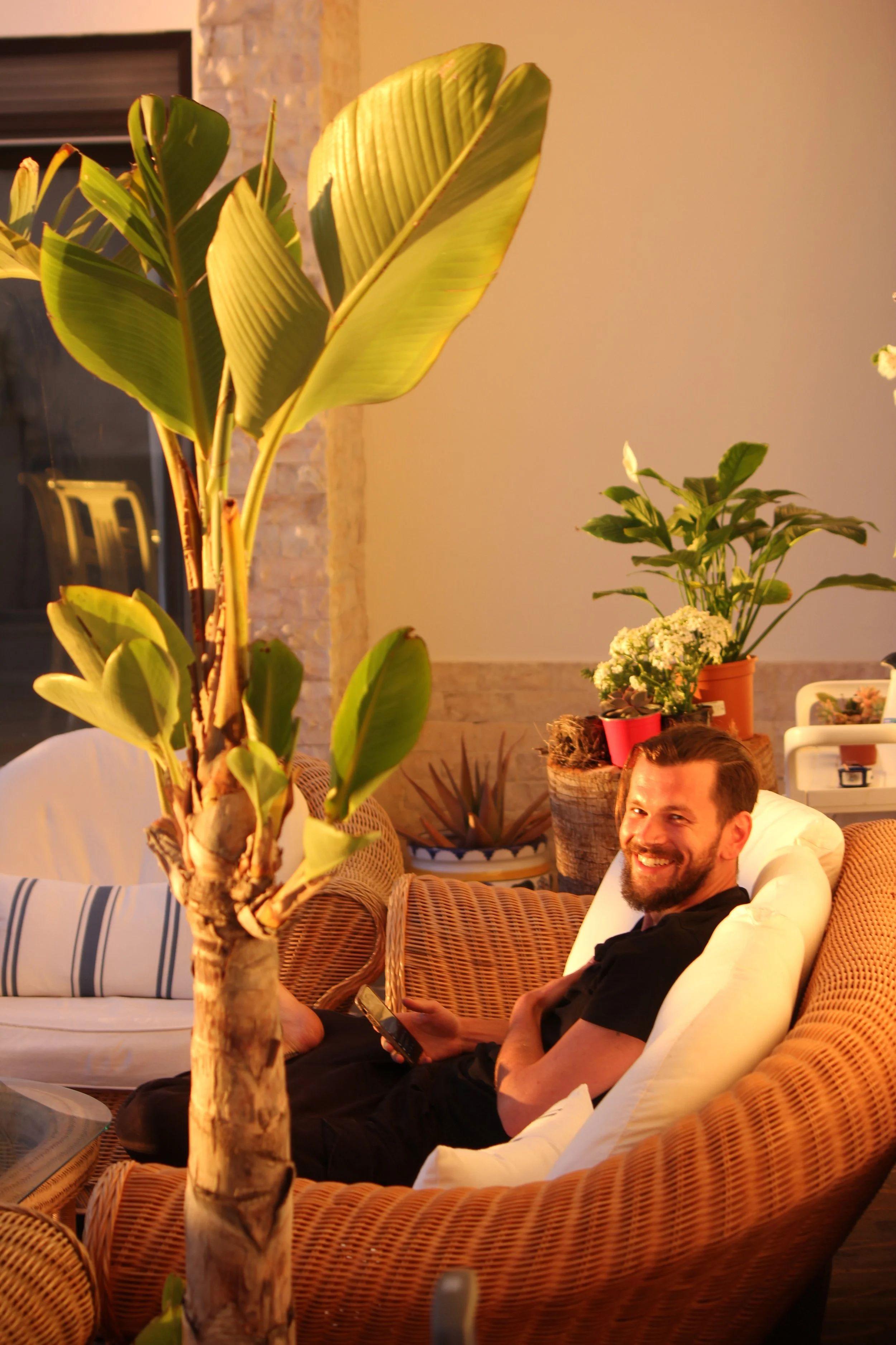 Guest relaxing in the indoor chillout lounge area with wicker furniture and plants