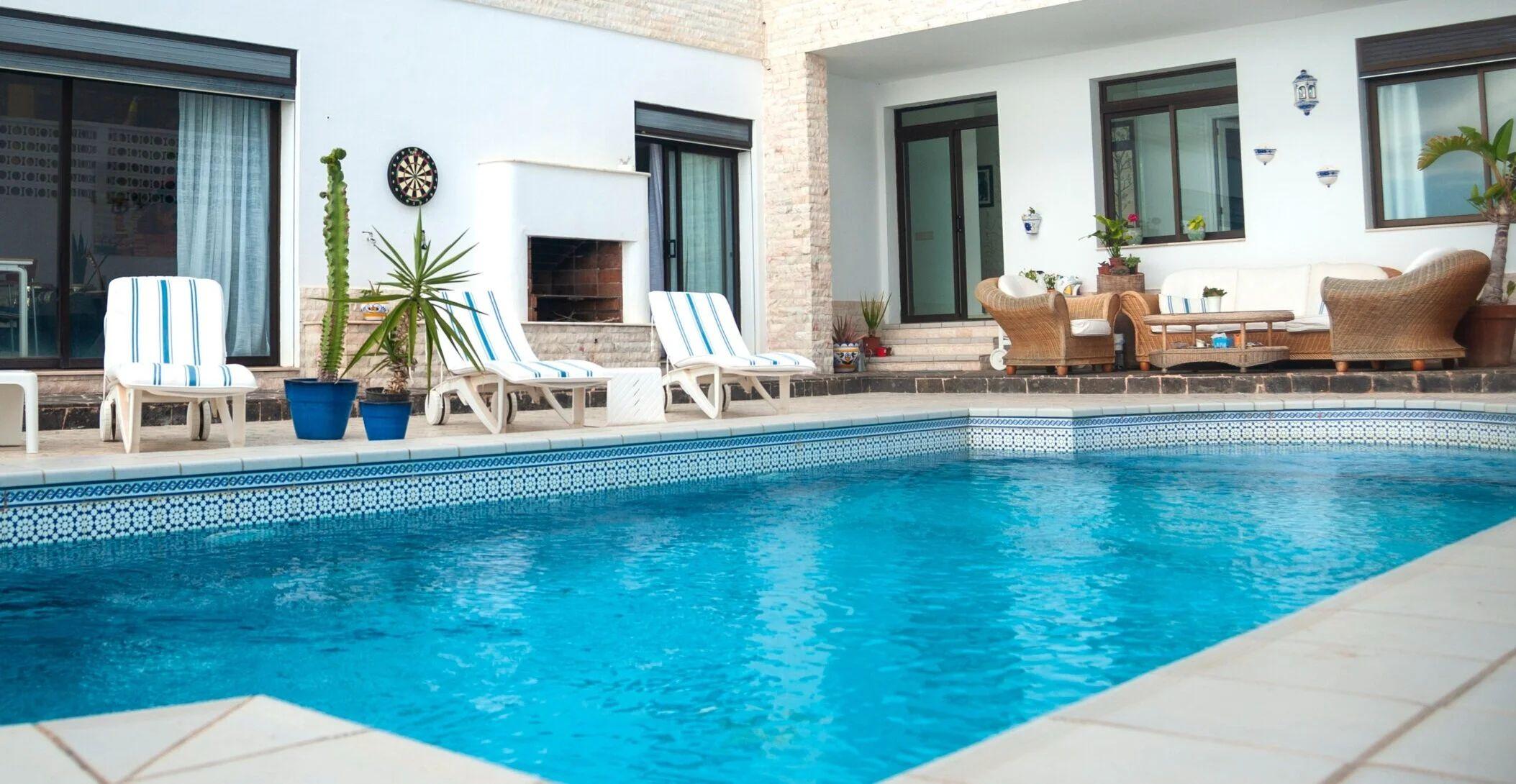 Outdoor swimming pool with sun loungers and the coliving building in the background