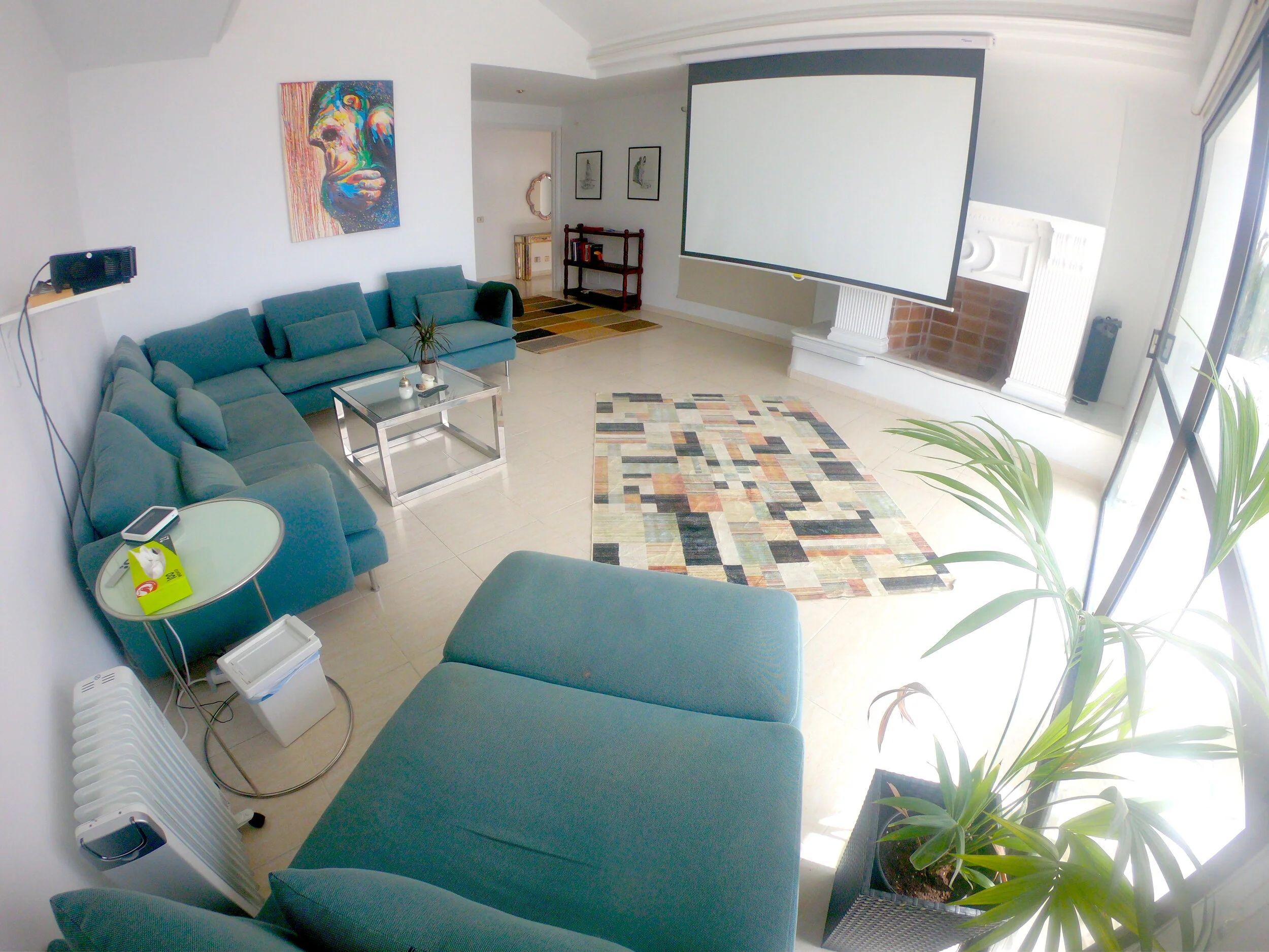 Indoor cinema room with large projection screen and blue sofas