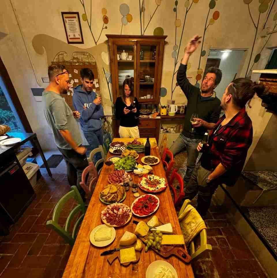Group of colivers gathered around a table laden with food and drinks for an apericena in the living room