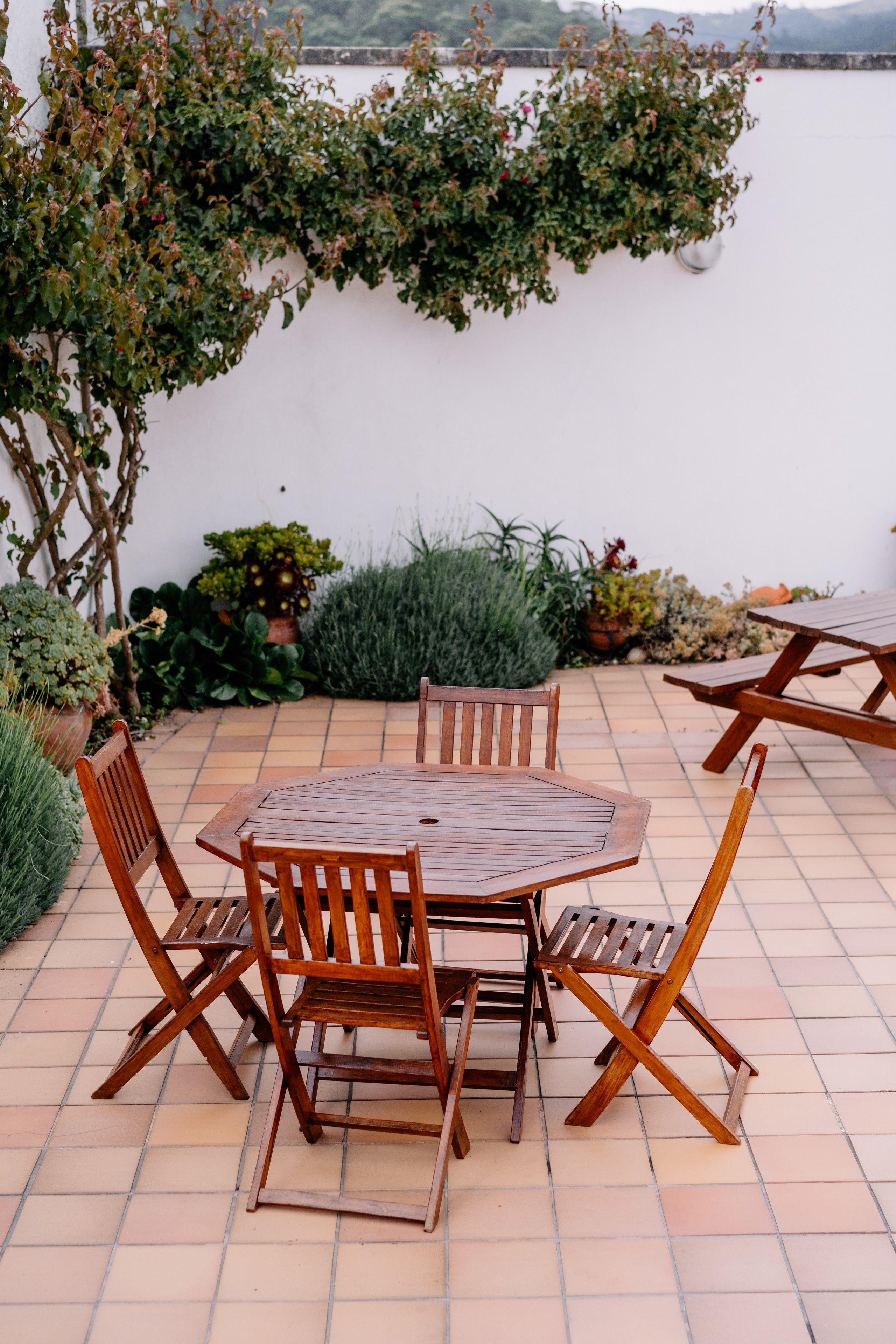 Outdoor tiled terrace with wooden table and chairs, surrounded by plants at Coliving The VALLEY