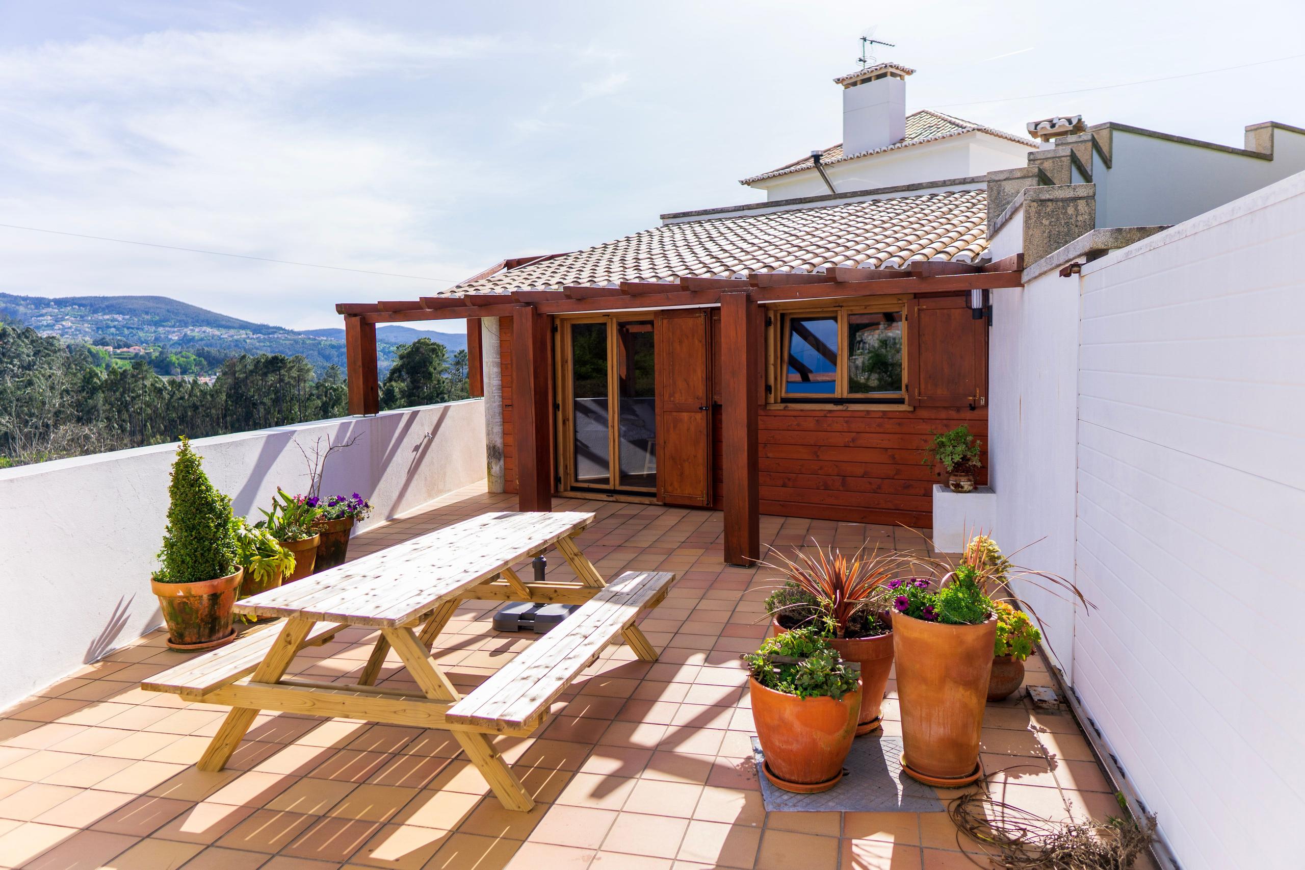 Outdoor tiled terrace with wooden picnic bench and the coworking wooden cabin entrance, with valley views