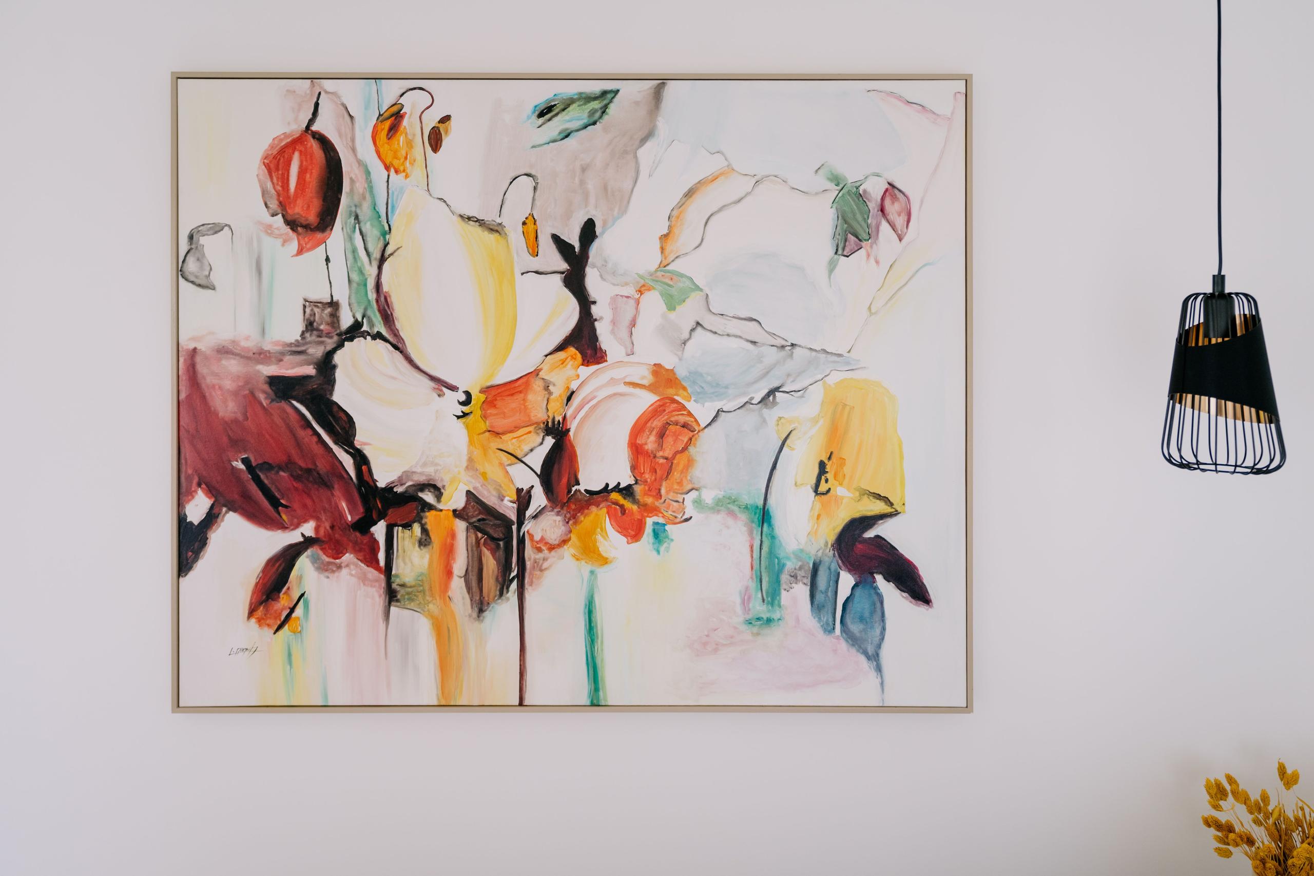 Bedroom interior showing a large colourful abstract painting on the wall with a pendant lamp