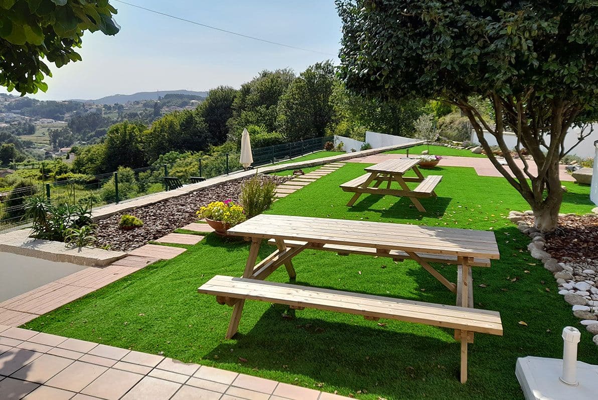 Lush garden area with wooden picnic tables and benches, panoramic valley views in the background