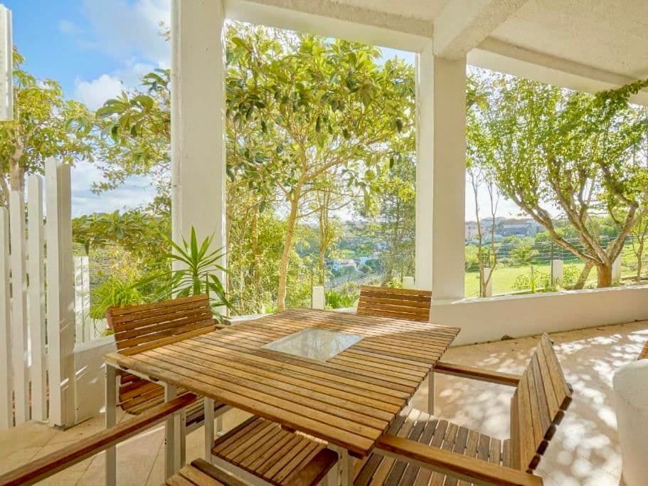 Covered outdoor terrace with wooden tables and benches surrounded by lush greenery and views of the valley