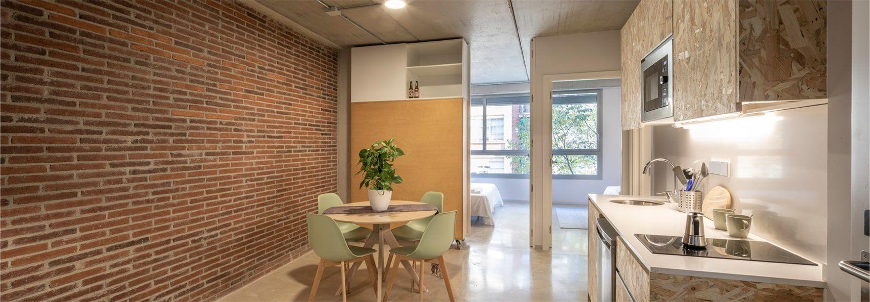 Coliving apartment showing dining area and kitchen with exposed brick wall