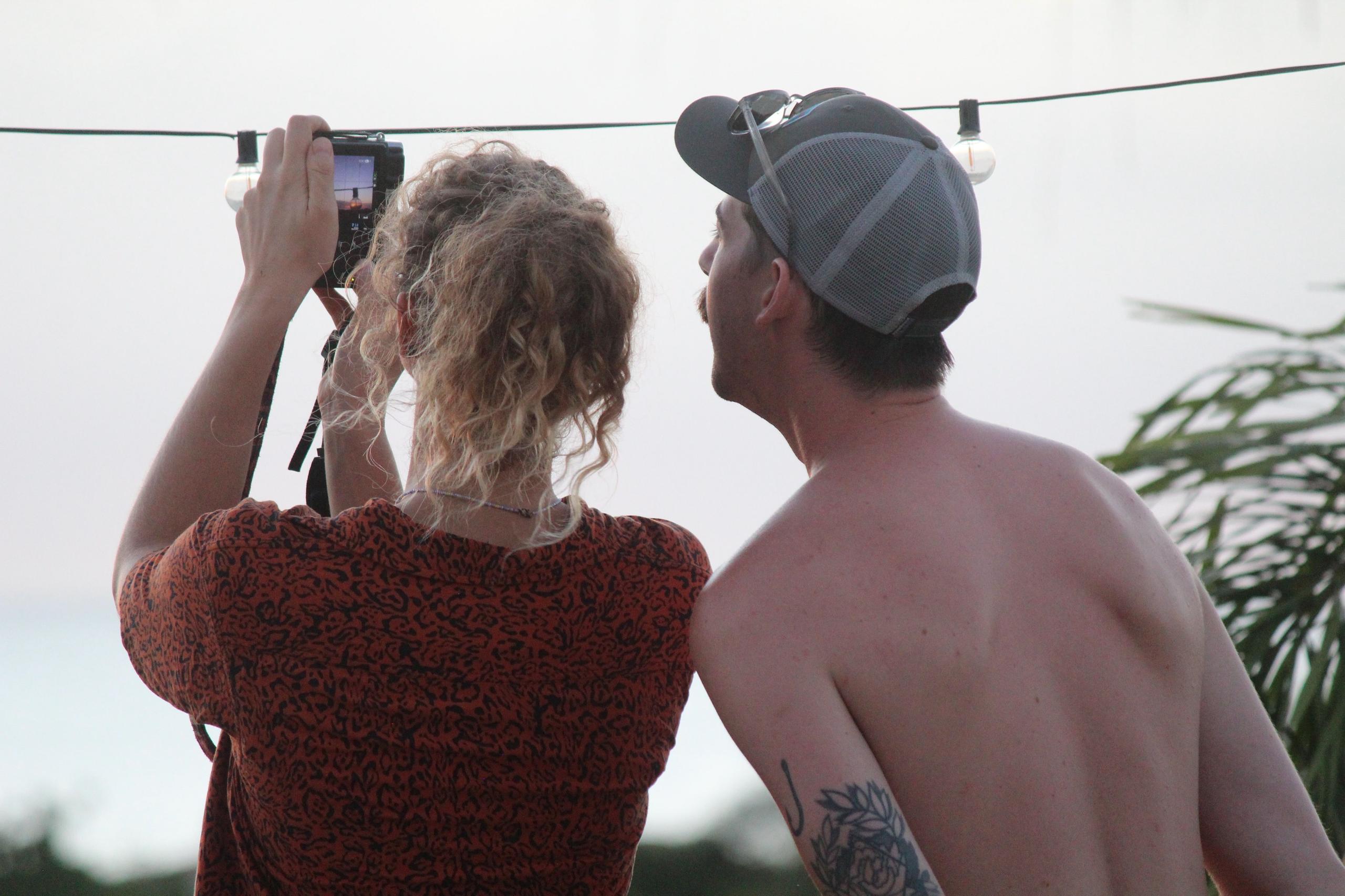 Two guests photographing the sunset from the rooftop