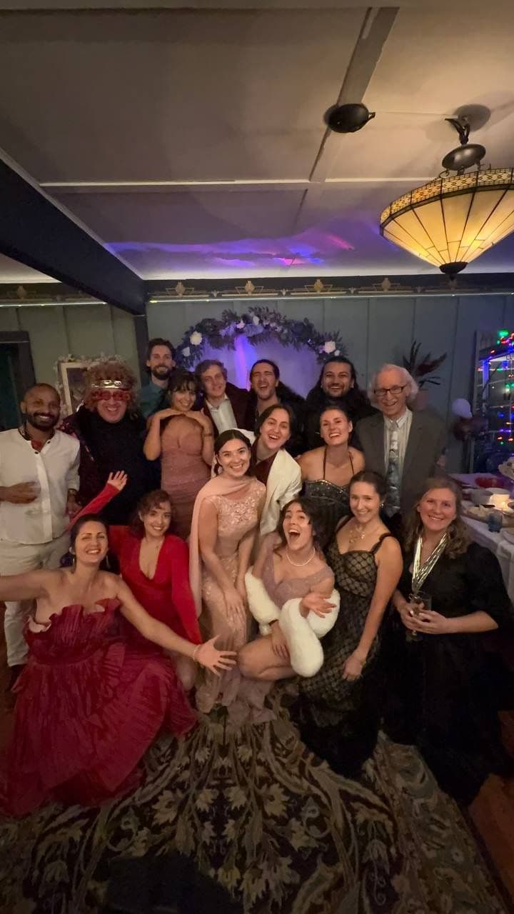 A group of people celebrating at a party in a decorated room, wearing formal and festive attire