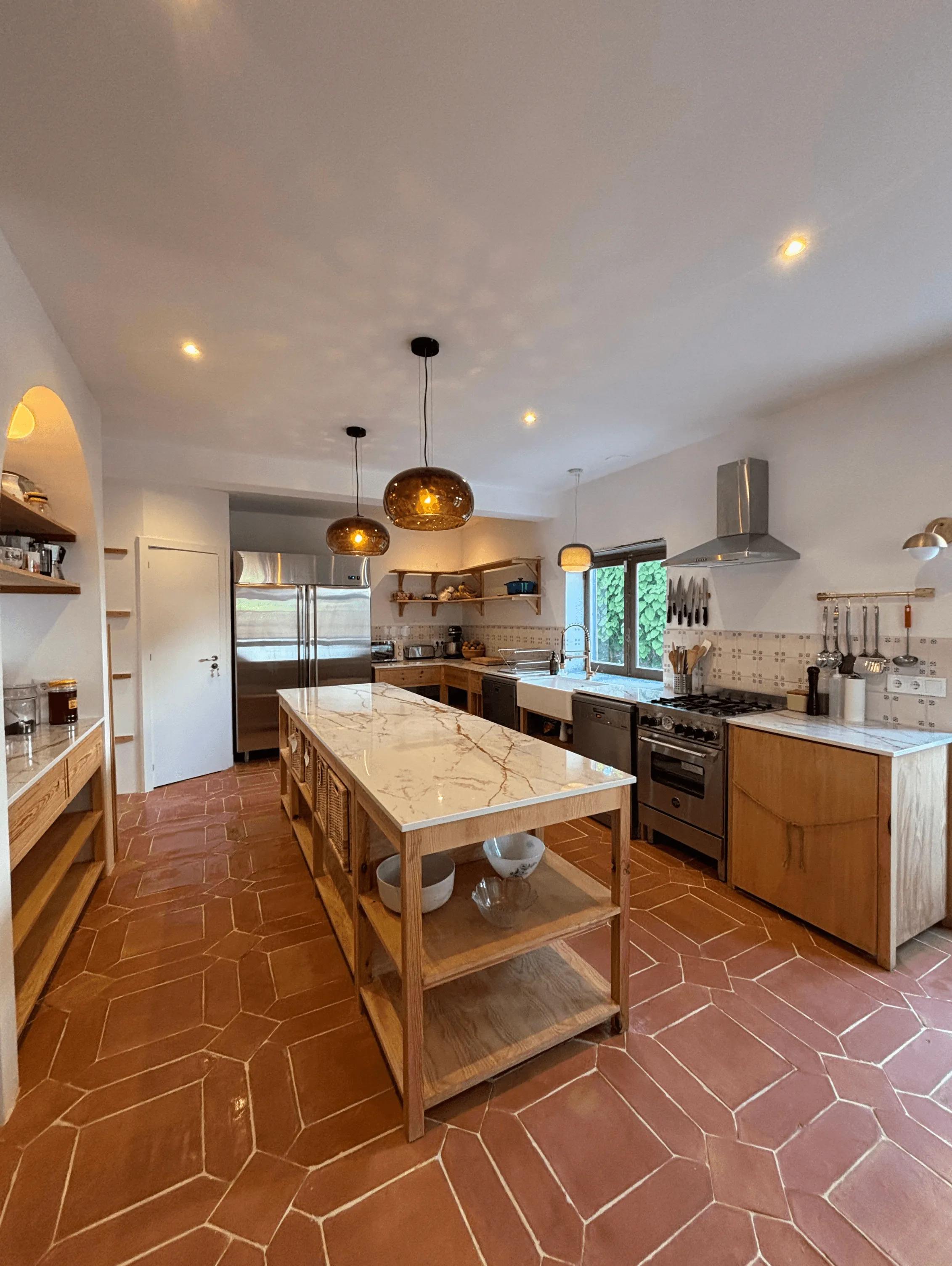 The gourmet kitchen at Wild Souls with marble island, terracotta tiles, and pendant lights