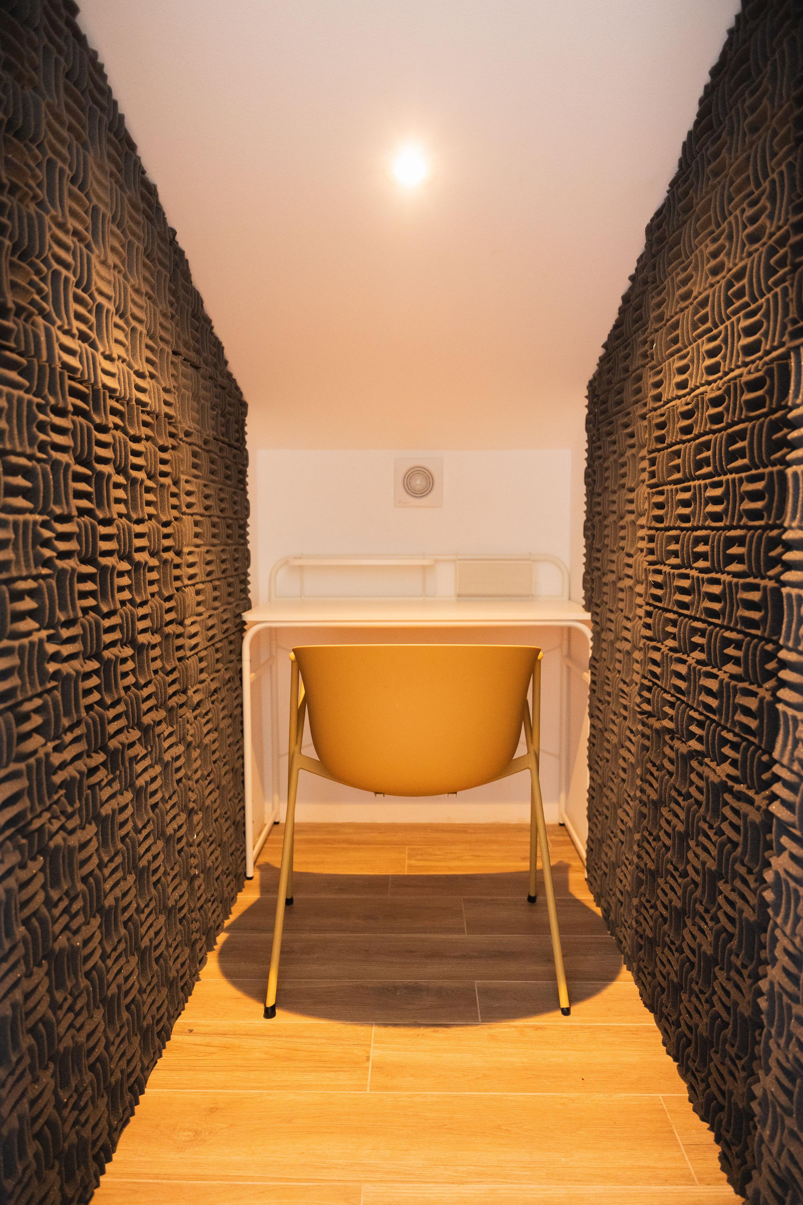 Interior of a sound-dampening phone booth with acoustic walls, desk and chair